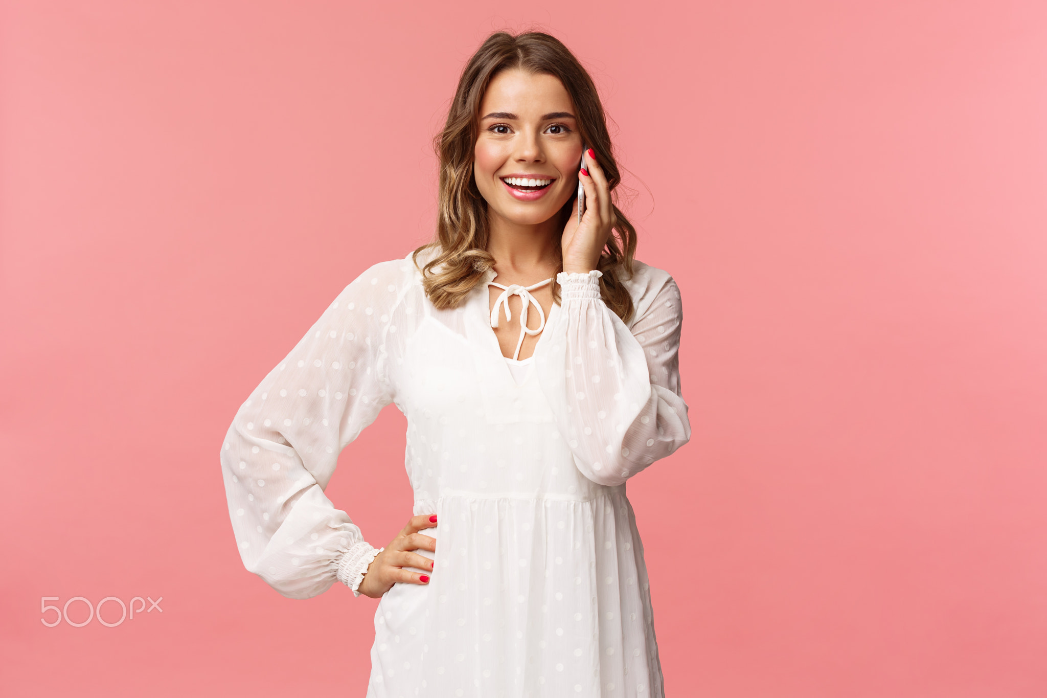 Portrait of joyful good-looking blond woman in white dress, talking on