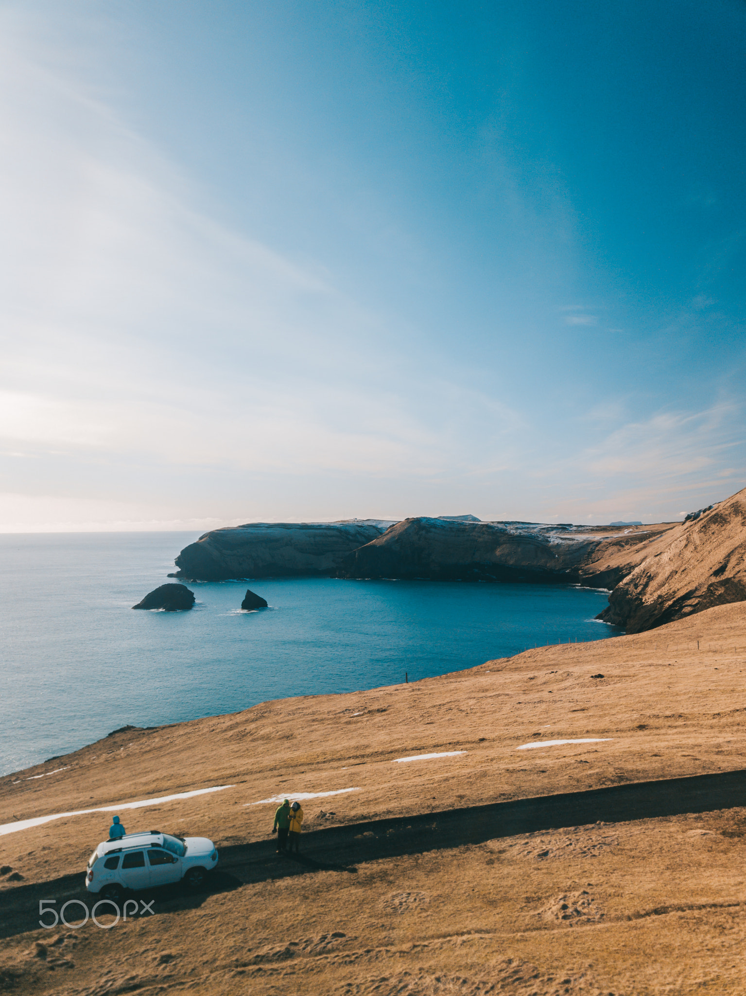 Gravel road at sunset with Vestrahorn mountain and a car driving