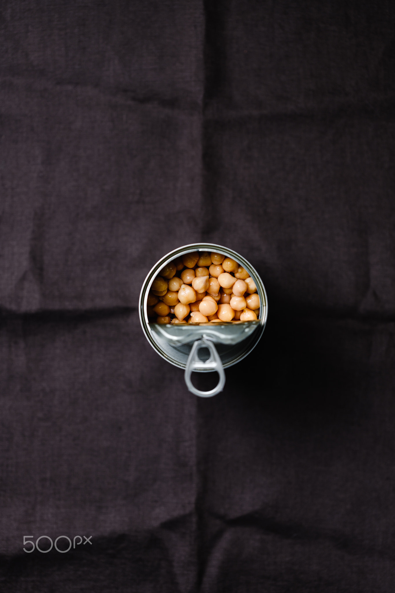 Opened can of chickpeas on a dark background.