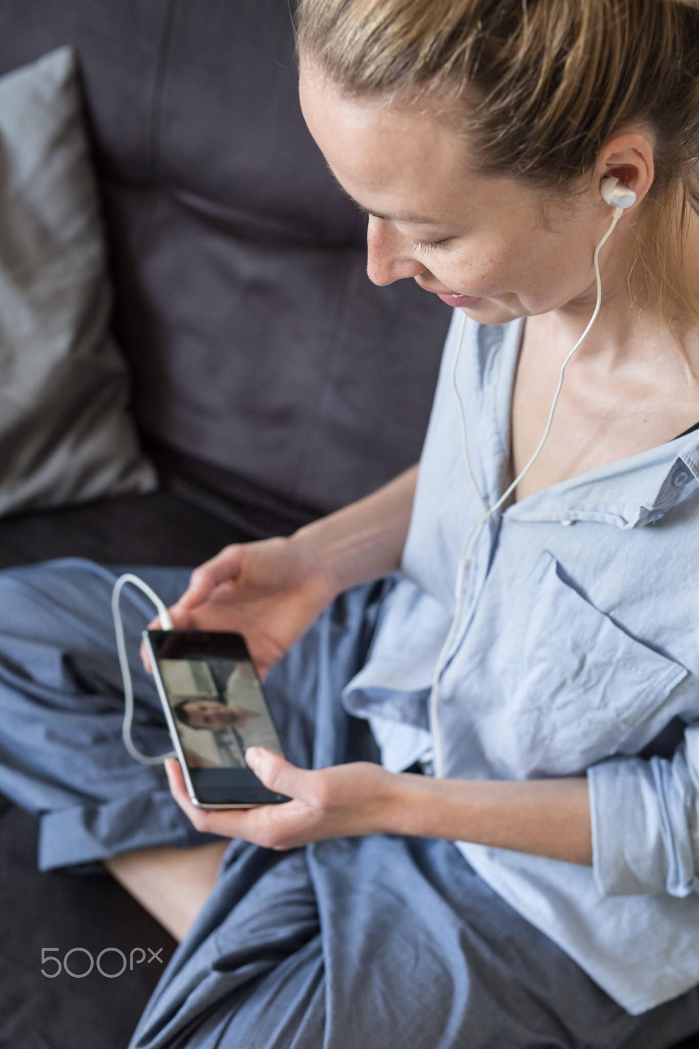 Woman at home relaxing on sofa couch using social media on phone for