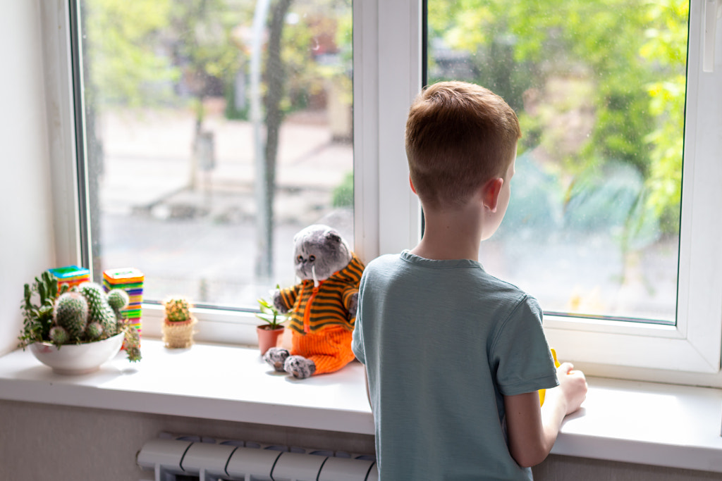 Young boy looking at window. He is sad and unhappy. Self isolation by Irina K on 500px.com