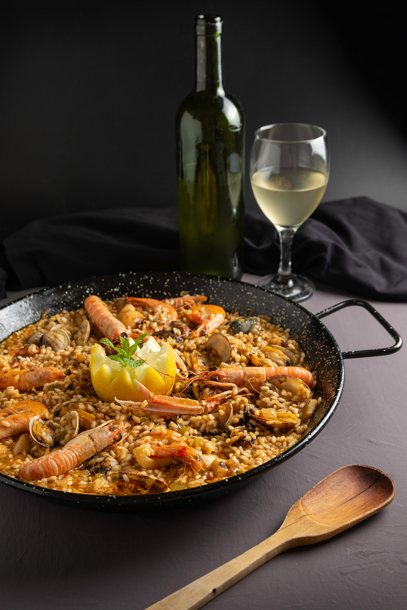 Seafood paella in rustic setting, cloudy wine
