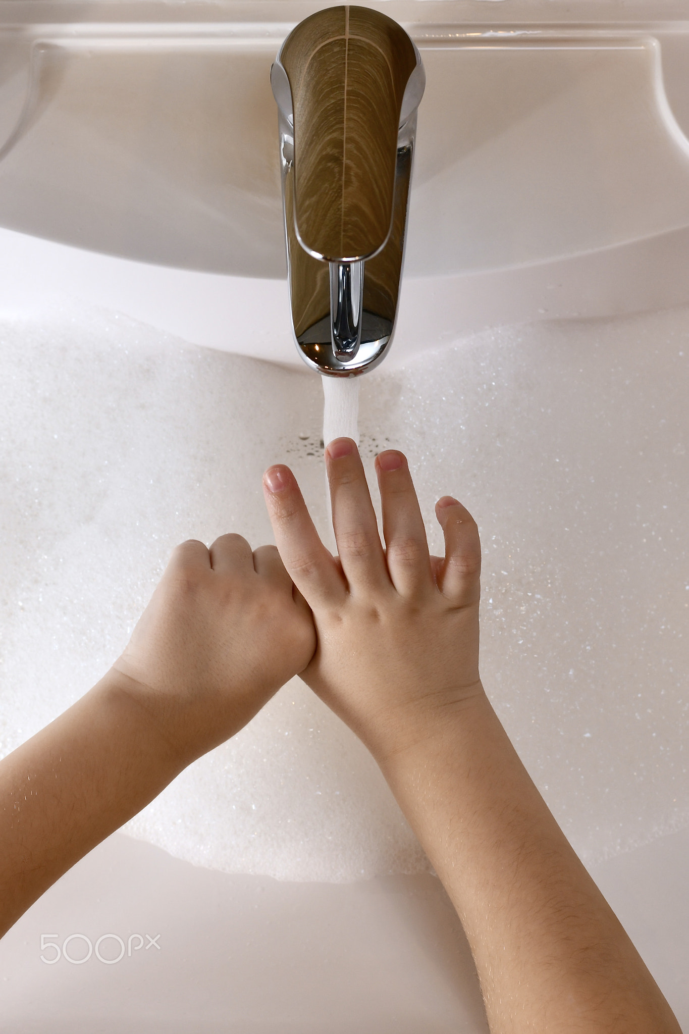 The child learns to wash the thumb area, with water in the sink.