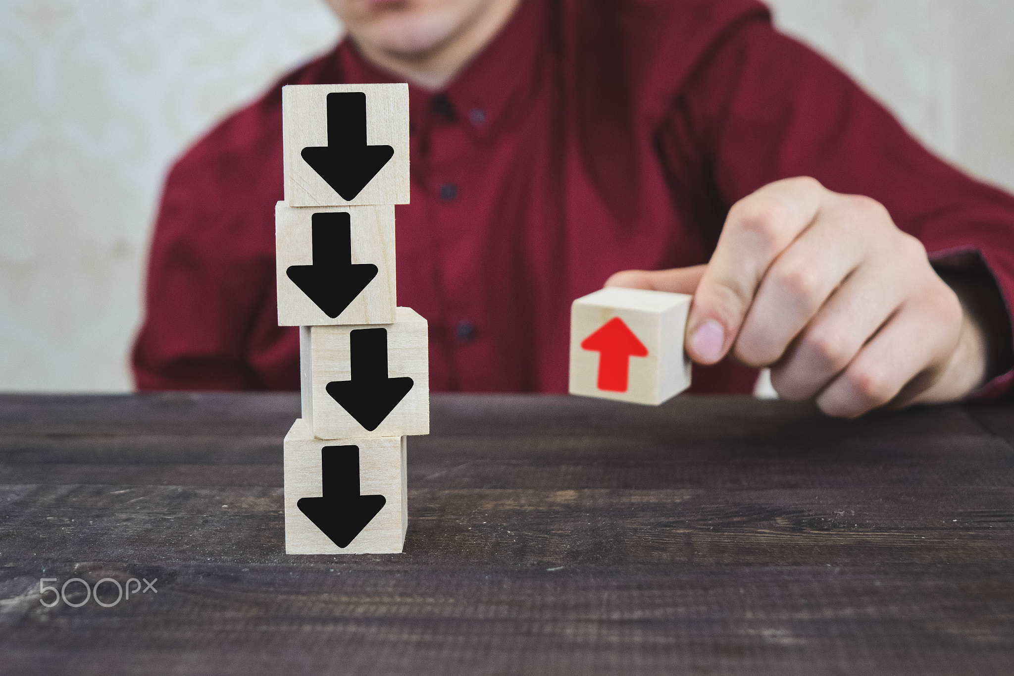 a person pulls one of the wooden cubes standing on the table, all of