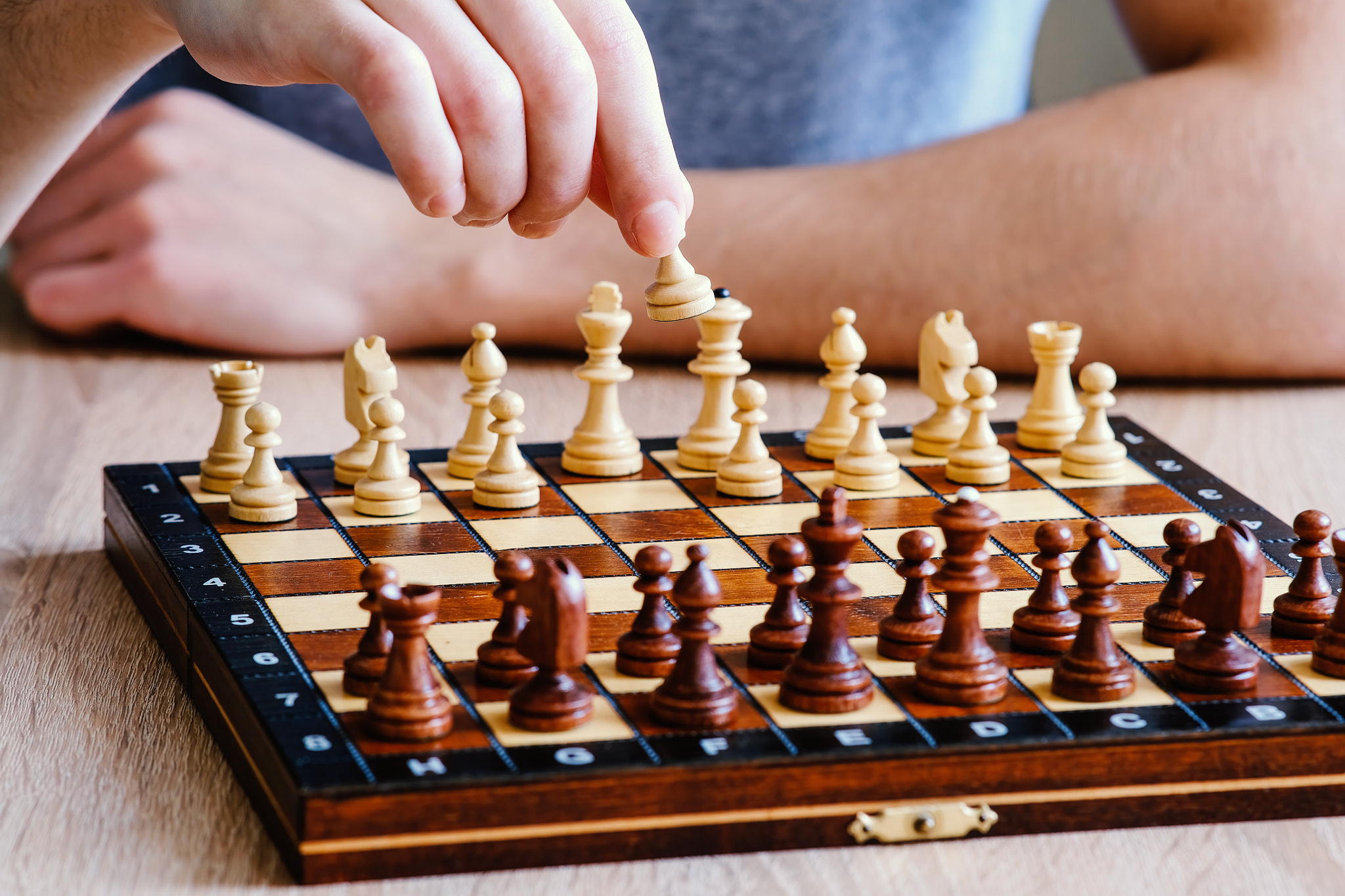 A chess player picks up a pawn and makes a move in a chess game.