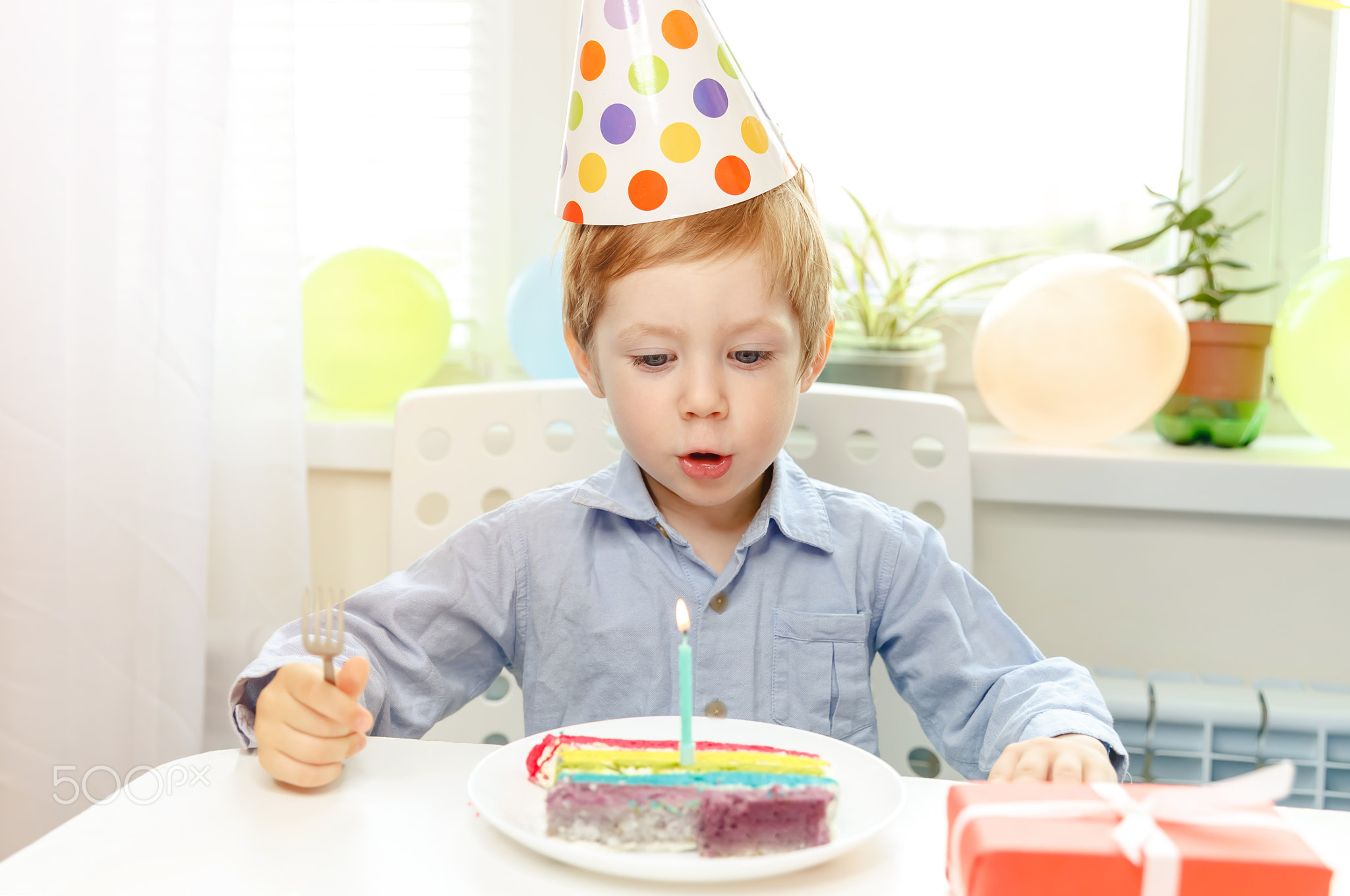 Birthday boy looking at candle on birthday cake. Birthday party