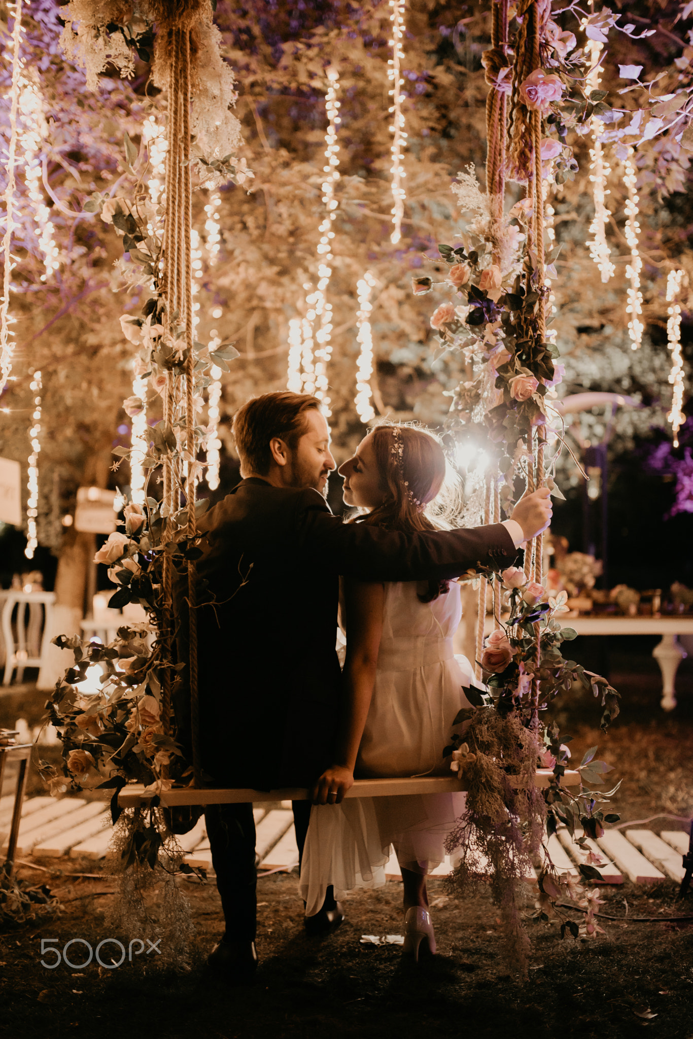newlyweds kiss after a wedding in a decorated forest on a swing