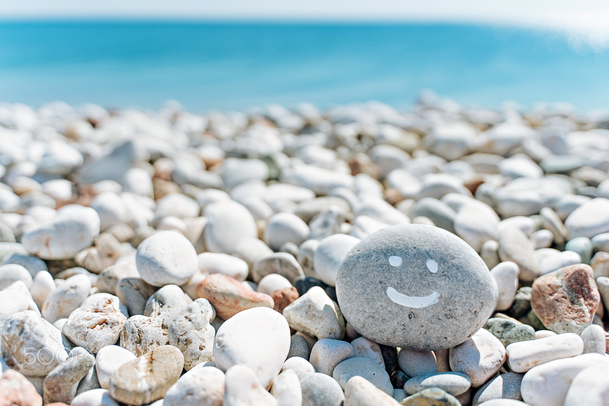 stones on the beach with a blue sea and the inscription smile