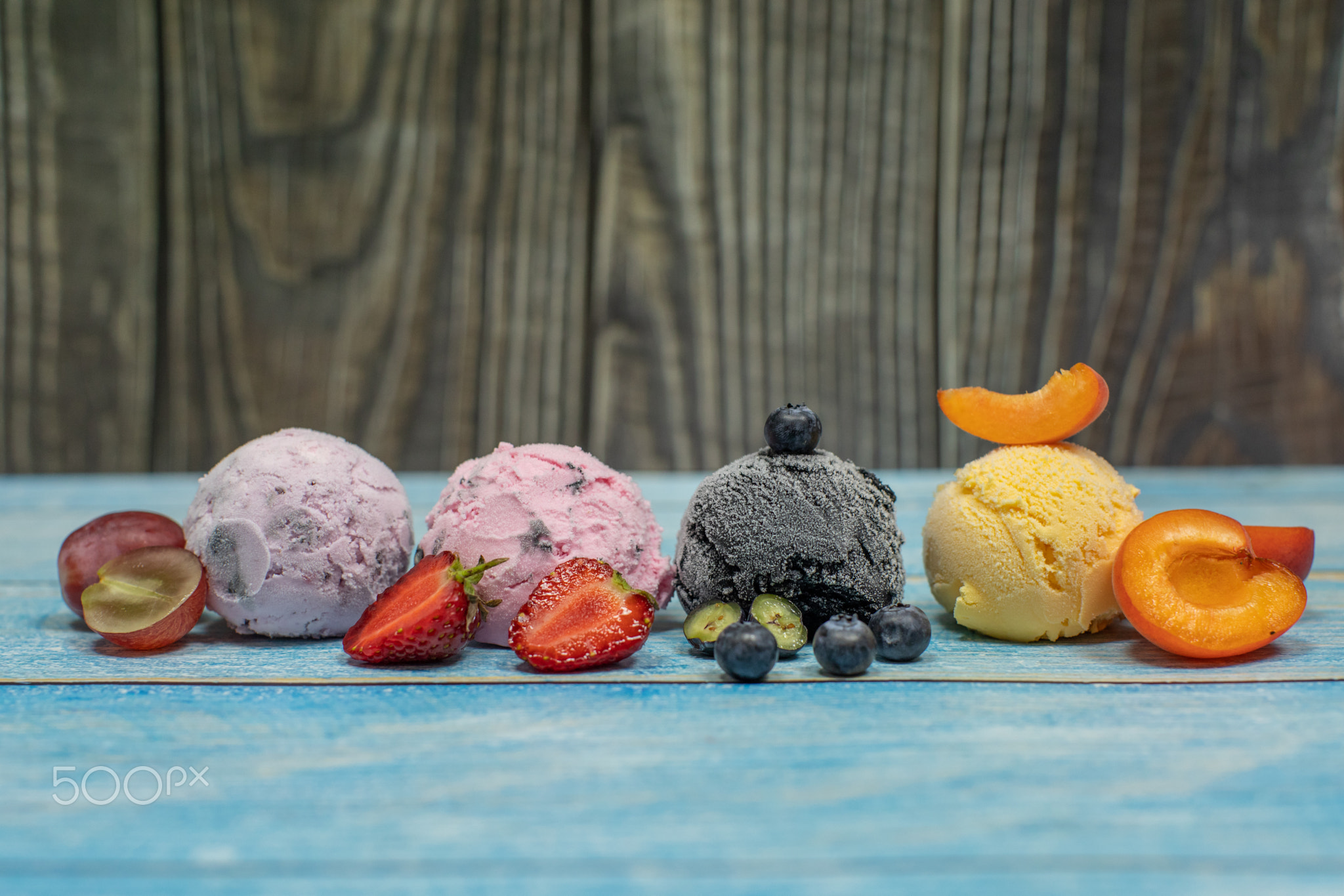 Sweet ice cream in balls on a wooden background. Different berries and