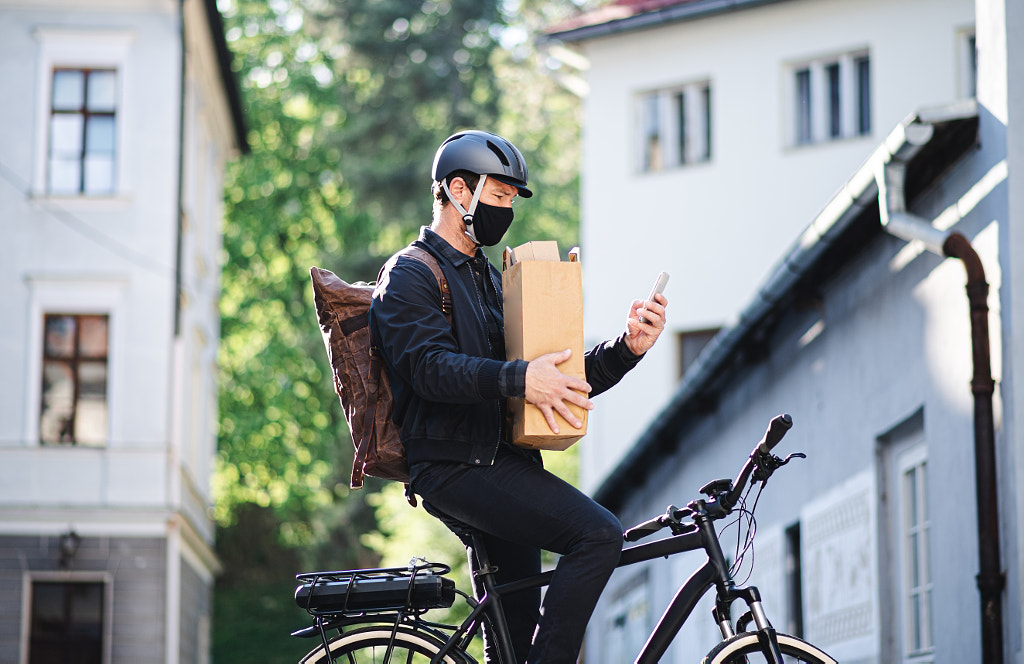 Delivery man courier with face mask and bicycle using smartphone in by Jozef Polc on 500px.com