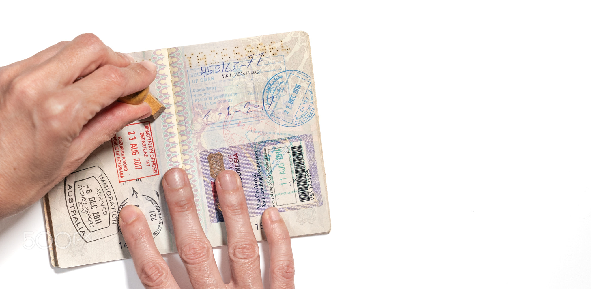 Stamping visa on passport pages with a lot of visa stamps.