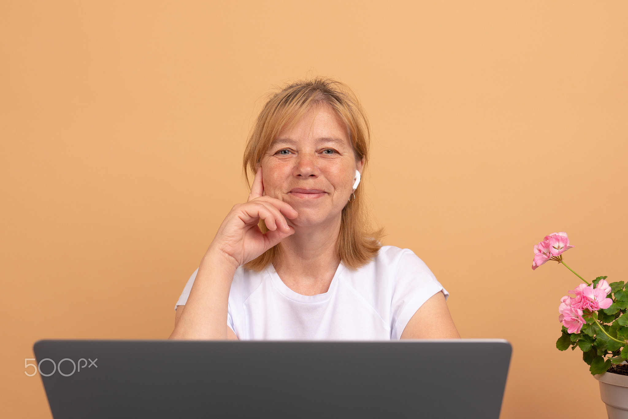 Smiling woman wearing wireless headphones working typing on notebook