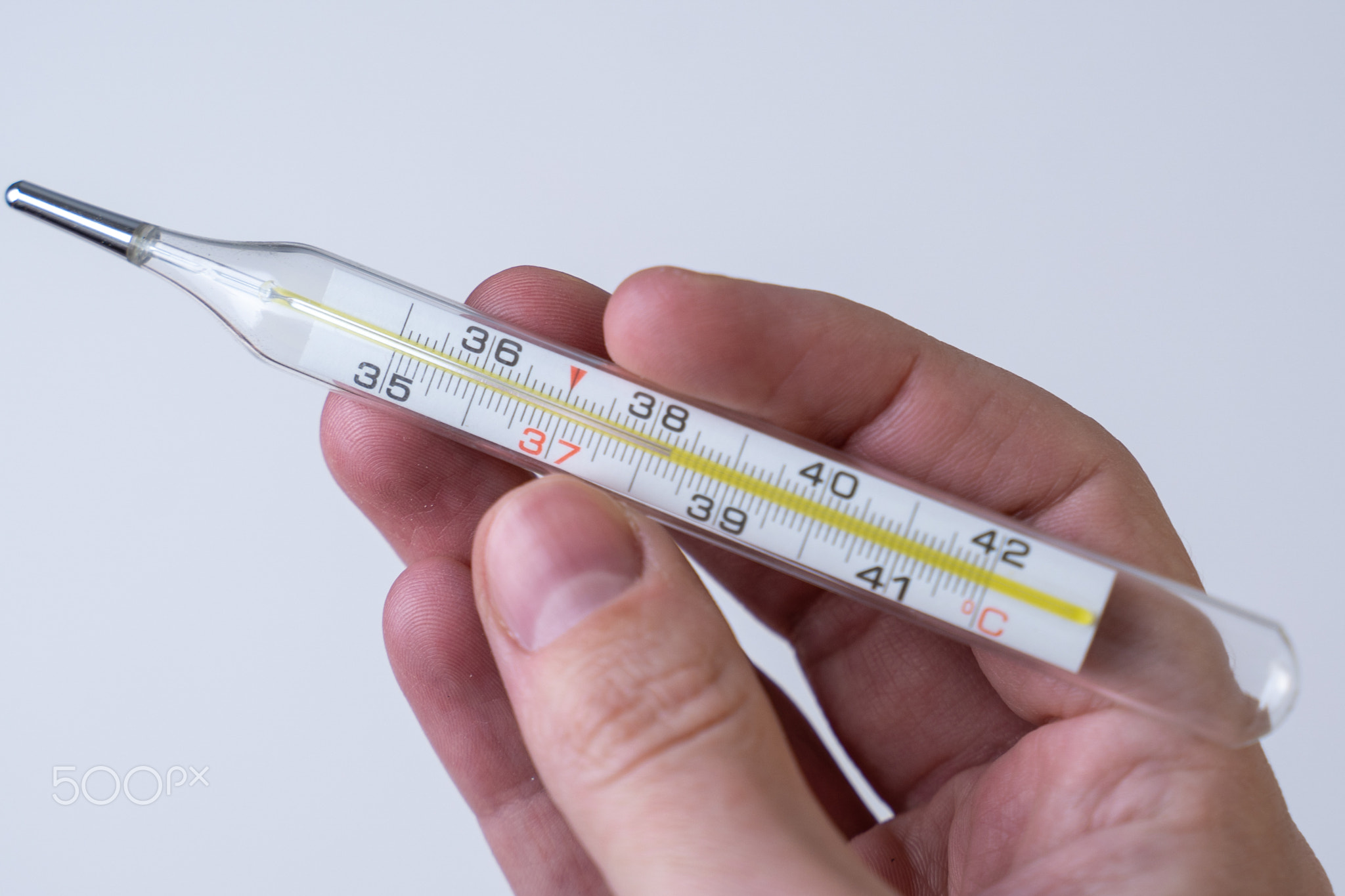A hand holding thermometer showing high body temperature