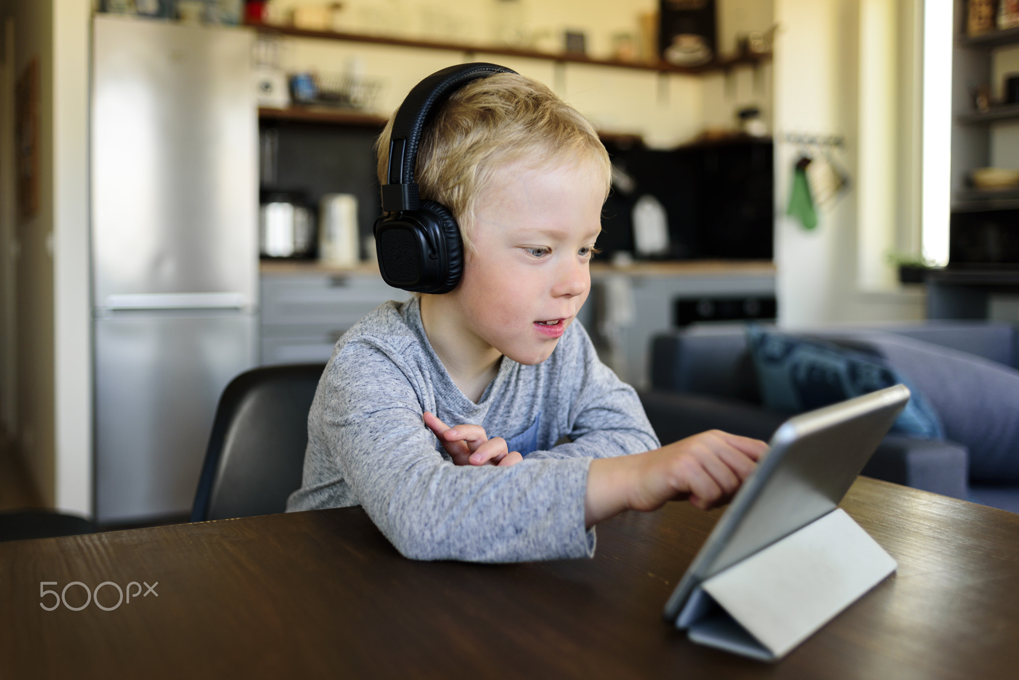 Little boy learning at home. Watching webinar on mobile tablet