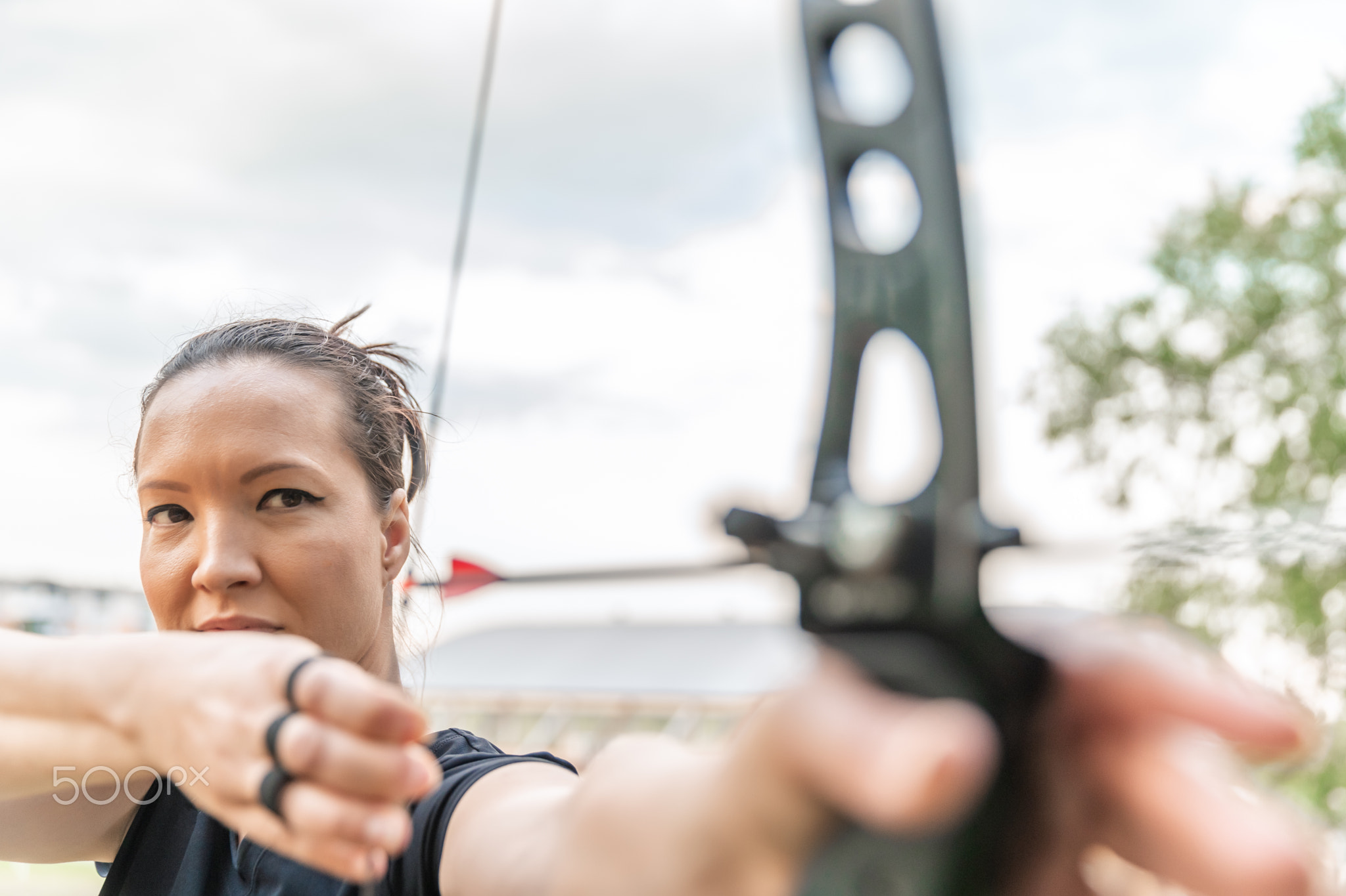 attractive spot woman stretching a bow string with an arrow on archery