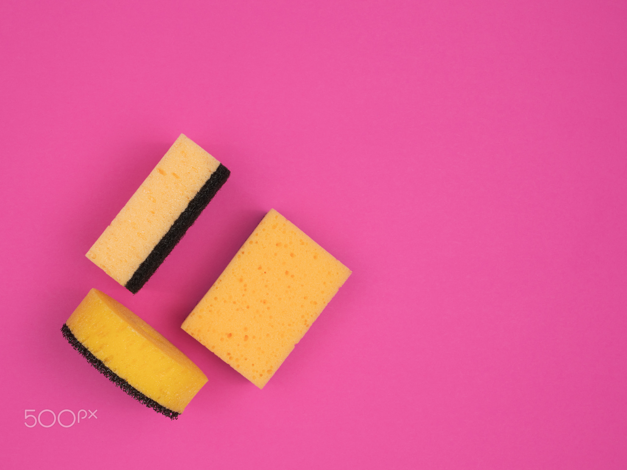 Different sponges for washing dishes and cleaning on a pink background