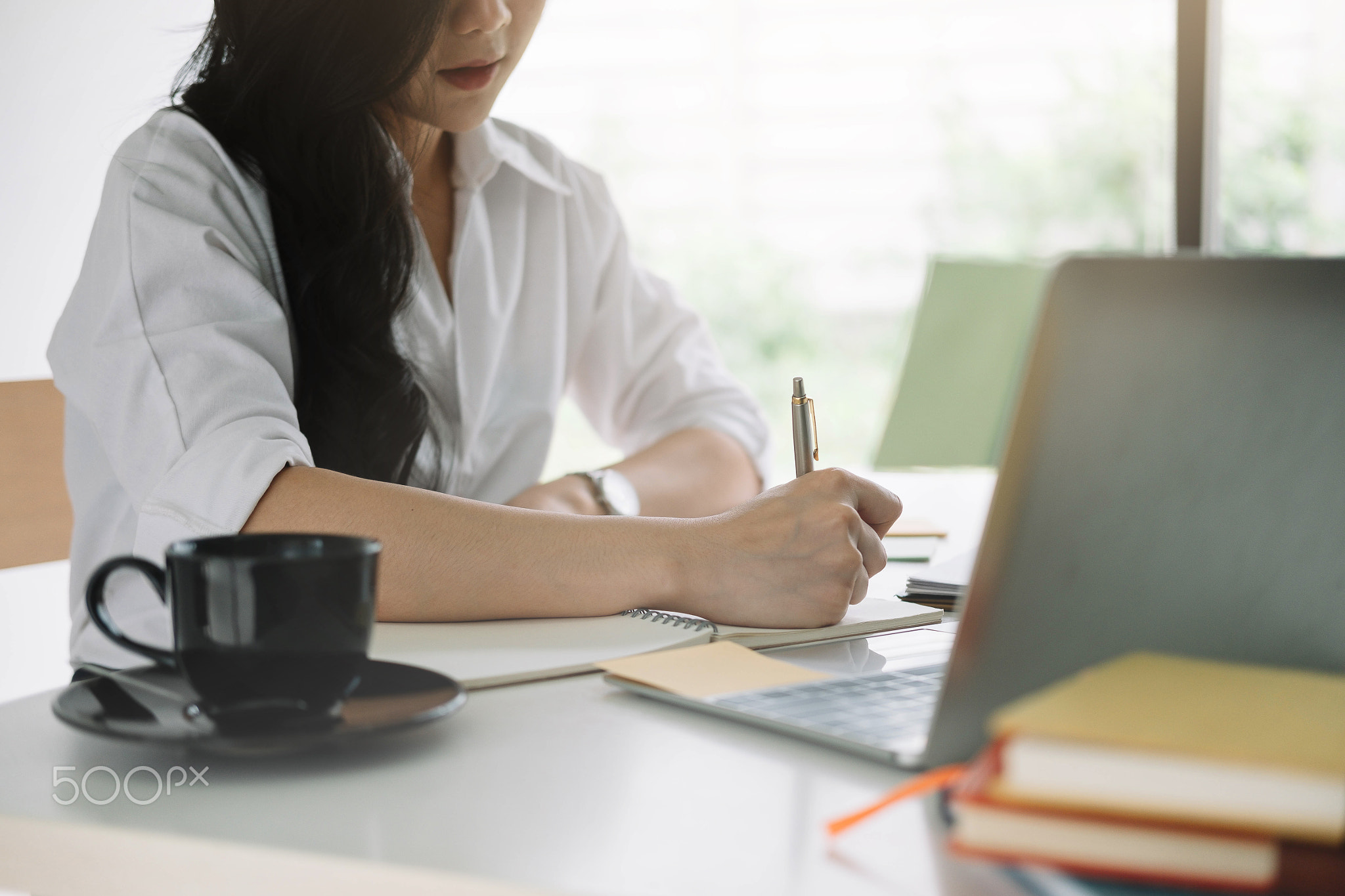 attractive woman writing in notepad while watching webinar on laptop