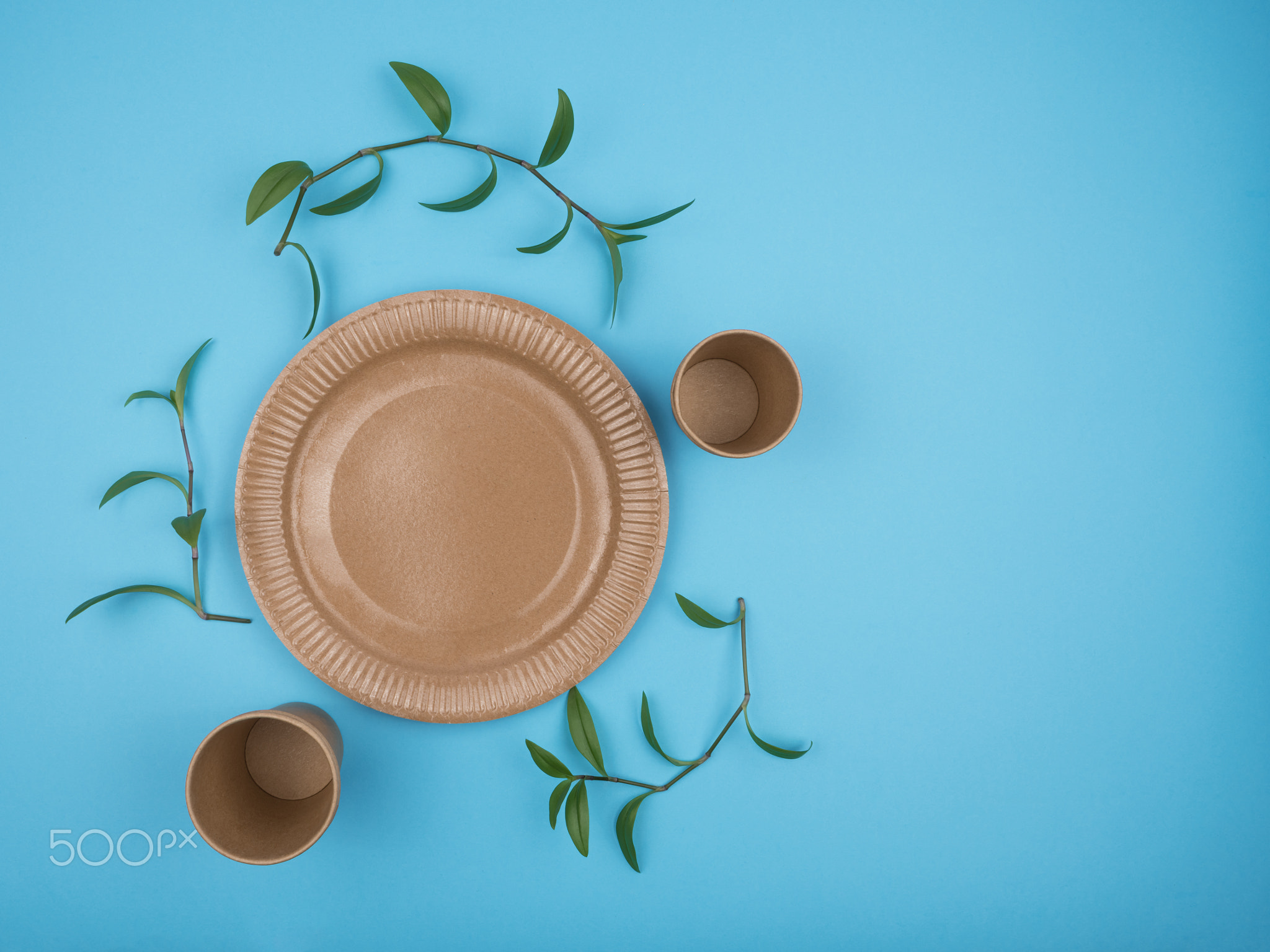 Paper disposable cups and plates on a blue background.