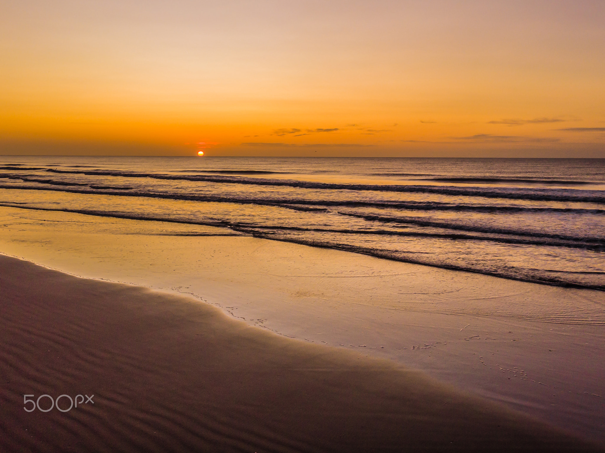 Sunrise over the sea near the beach. The sun very close to the horizon