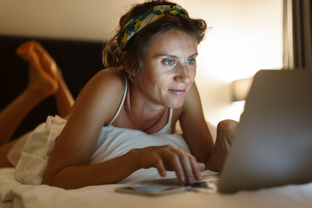 Young woman laying in bed and using her laptop before sleeping by Oleksandr Boiko on 500px.com