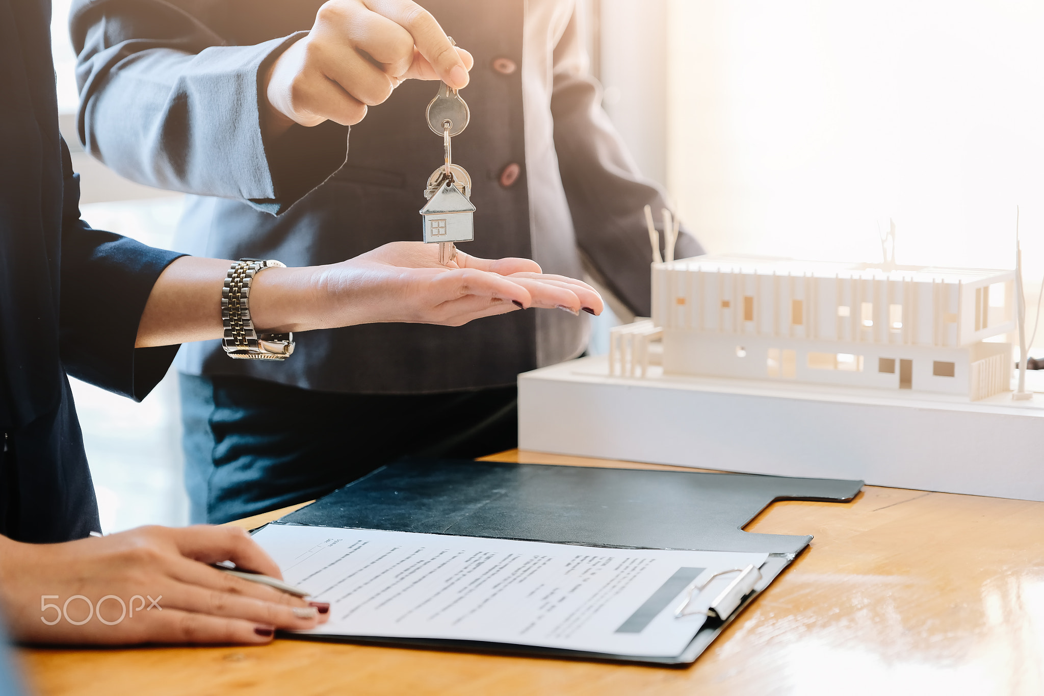 estate agent giving house keys to man and sign agreement in office