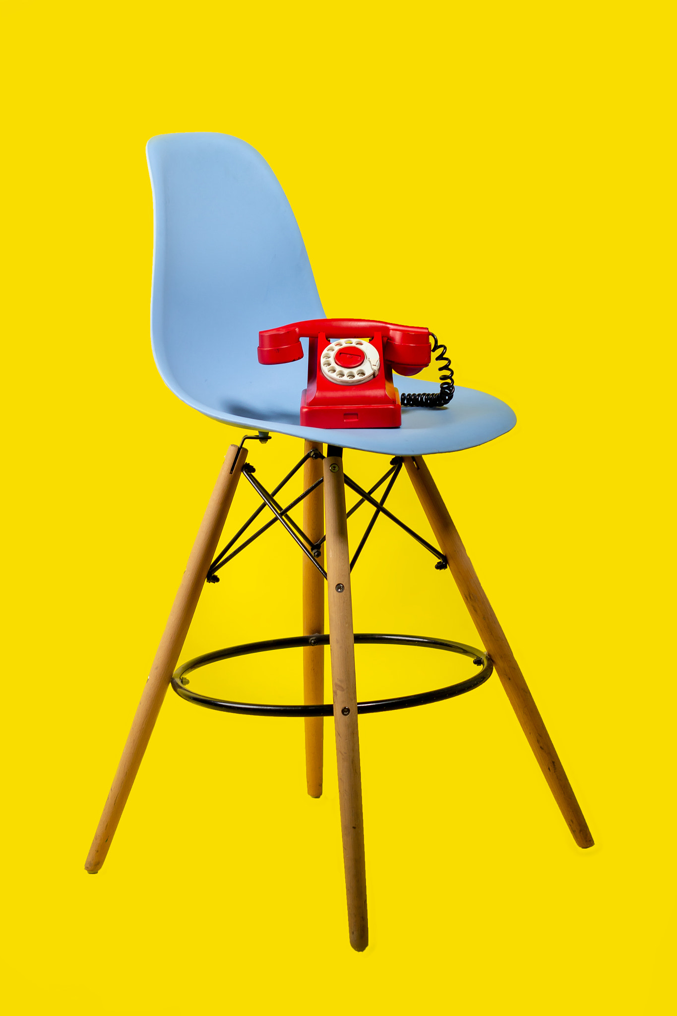 retro red telephone on a blue chair on yellow background 80s-90s