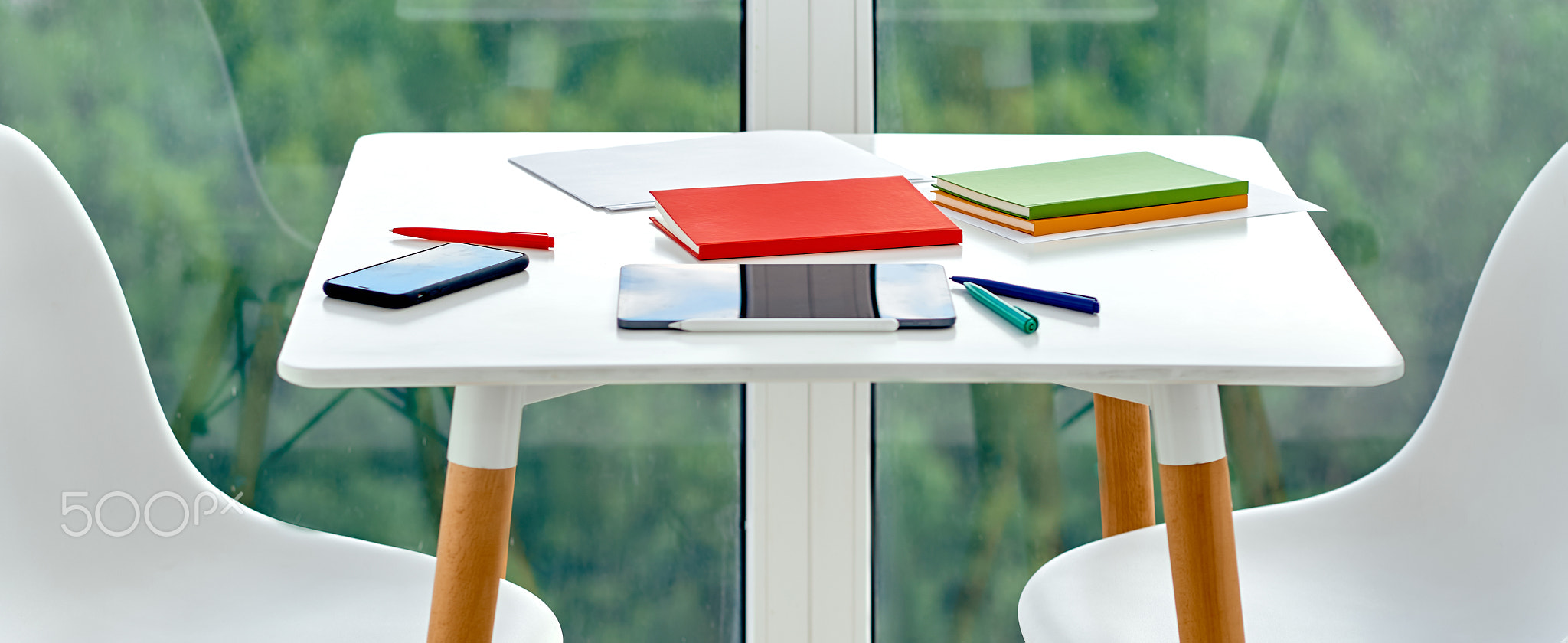 desktop with notepads with phone handles and a tablet on the balcony 