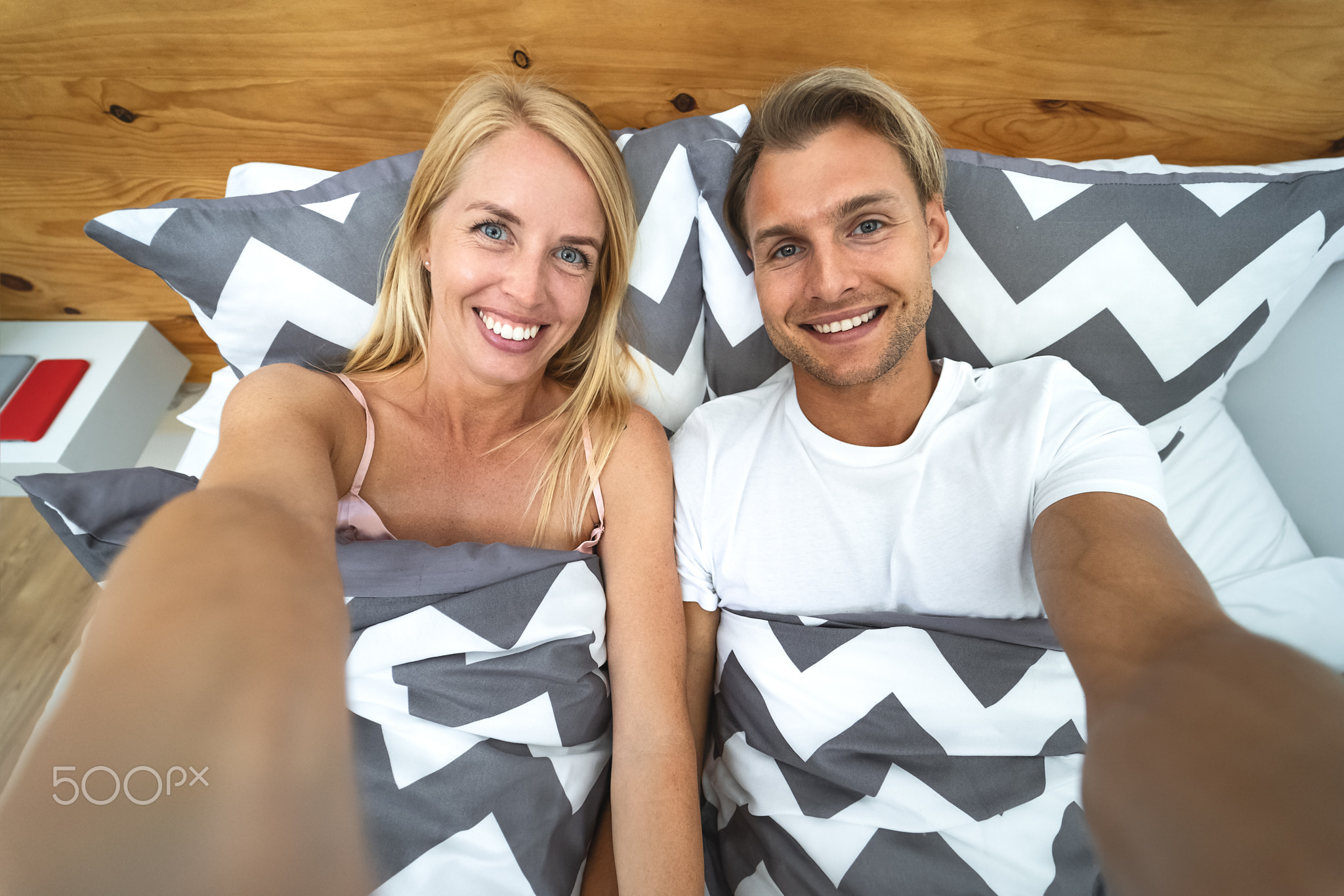 Young couple taking selfie in bed