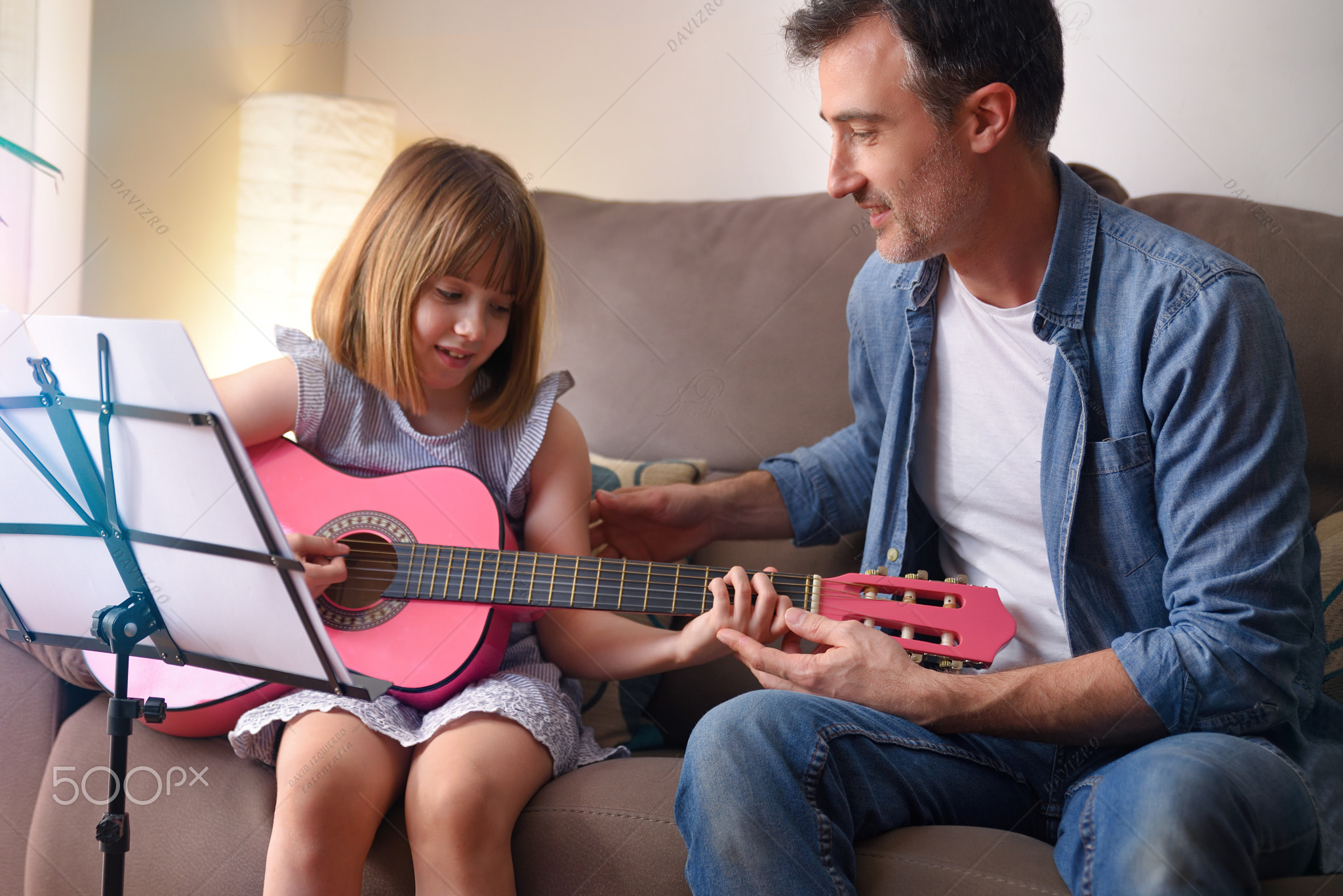 Guitar teacher teaching a girl in her living room detail