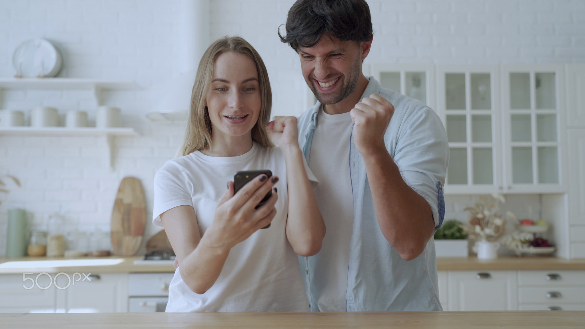 Couple at dining table in kitchen check lottery on-line app on