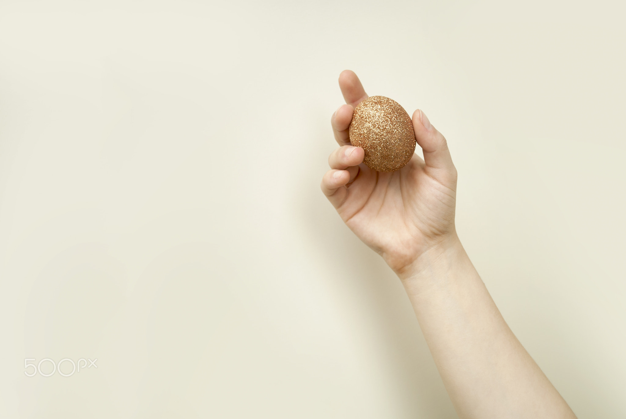 Minimalistic shot of women's hands holding golden egg