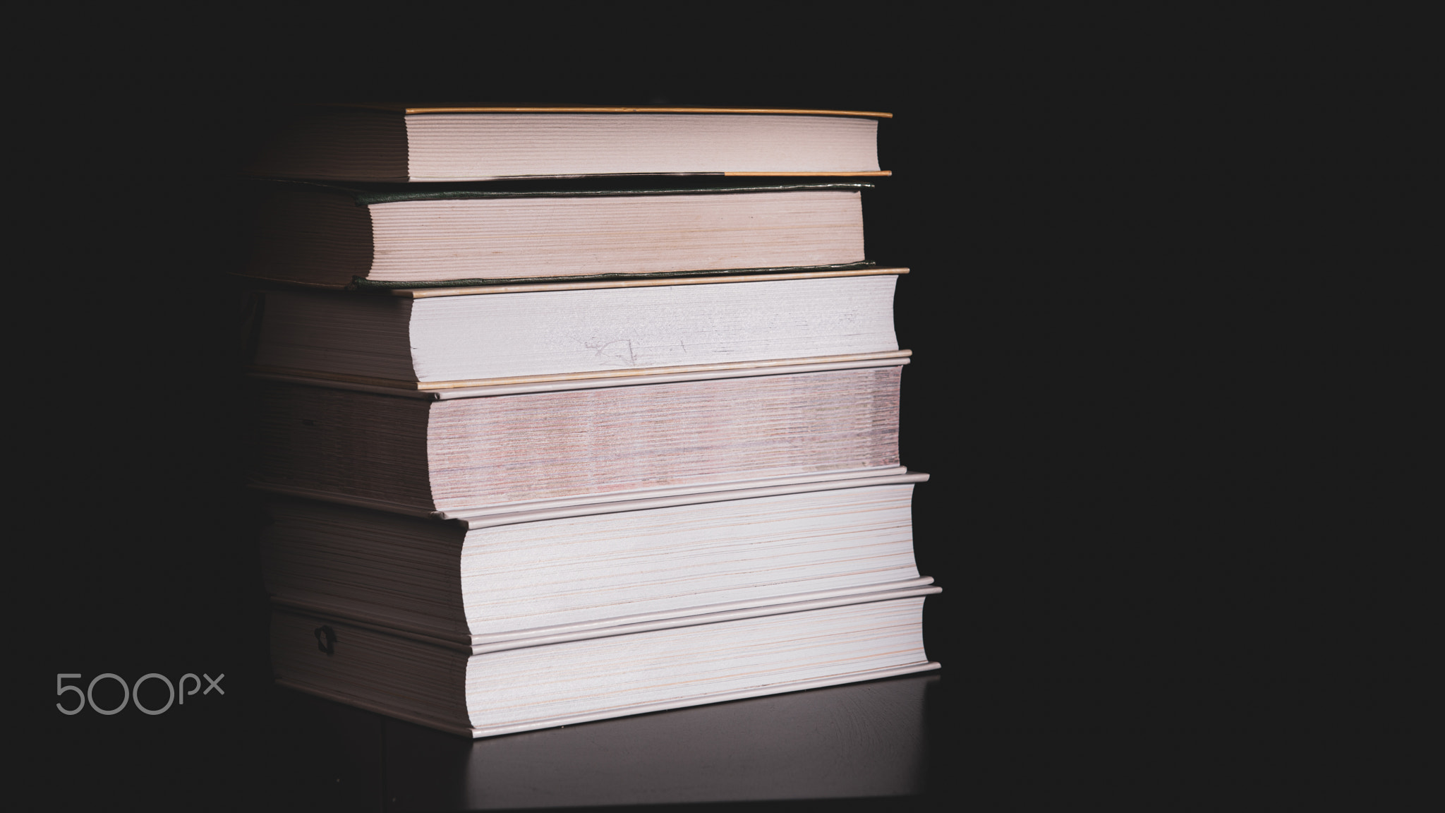 High messy stack of books on a black background with space for text