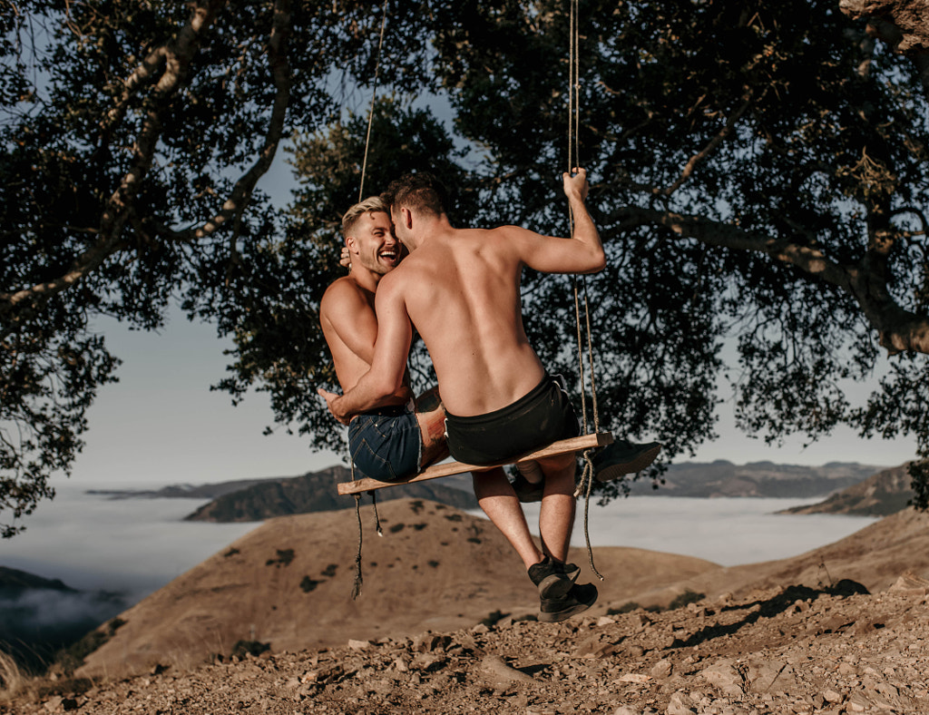 Young caucasian LGBTQI couple sitting together romantically outdoors by Kyle Kuhlman on 500px.com