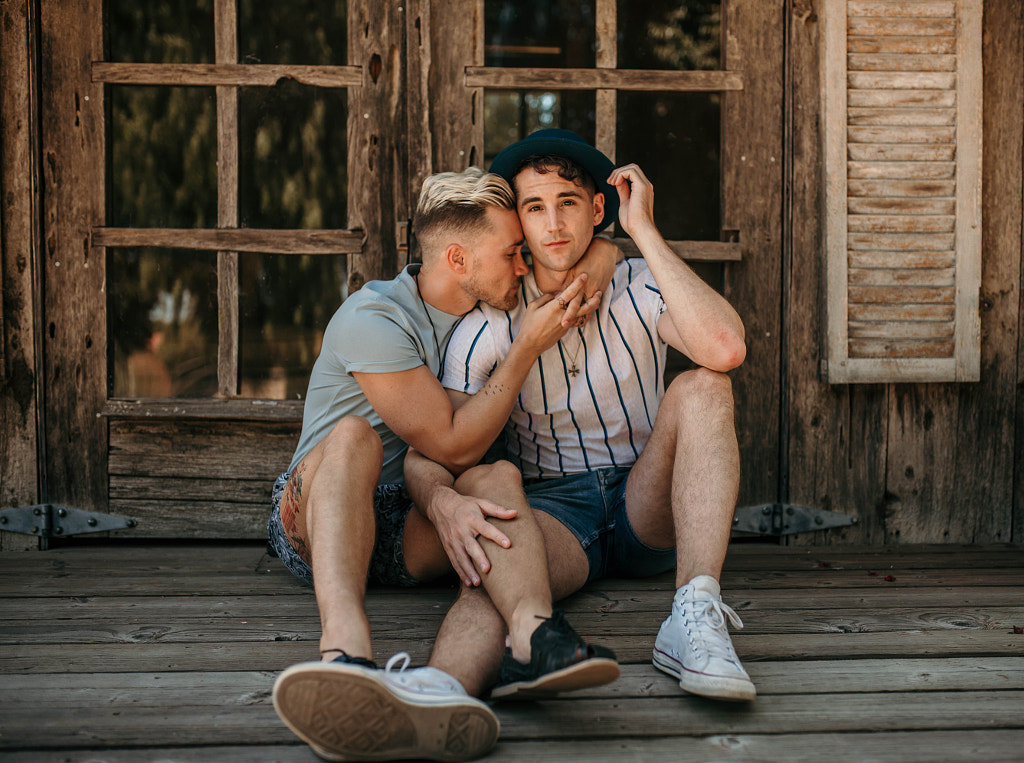 Young caucasian LGBTQI couple sitting together romantically outdoors by Kyle Kuhlman on 500px.com
