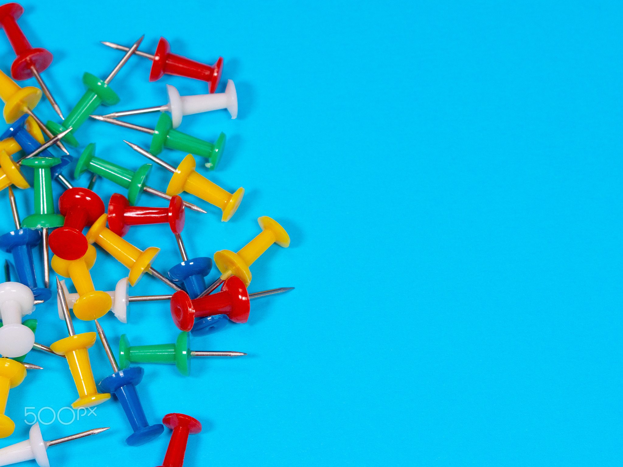 Color push pins on blue background for copyspace