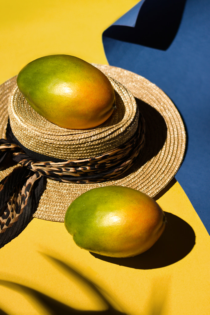 Summer tropical fruits mango and a hat on yellow blue paper background by Julia Kunz on 500px.com