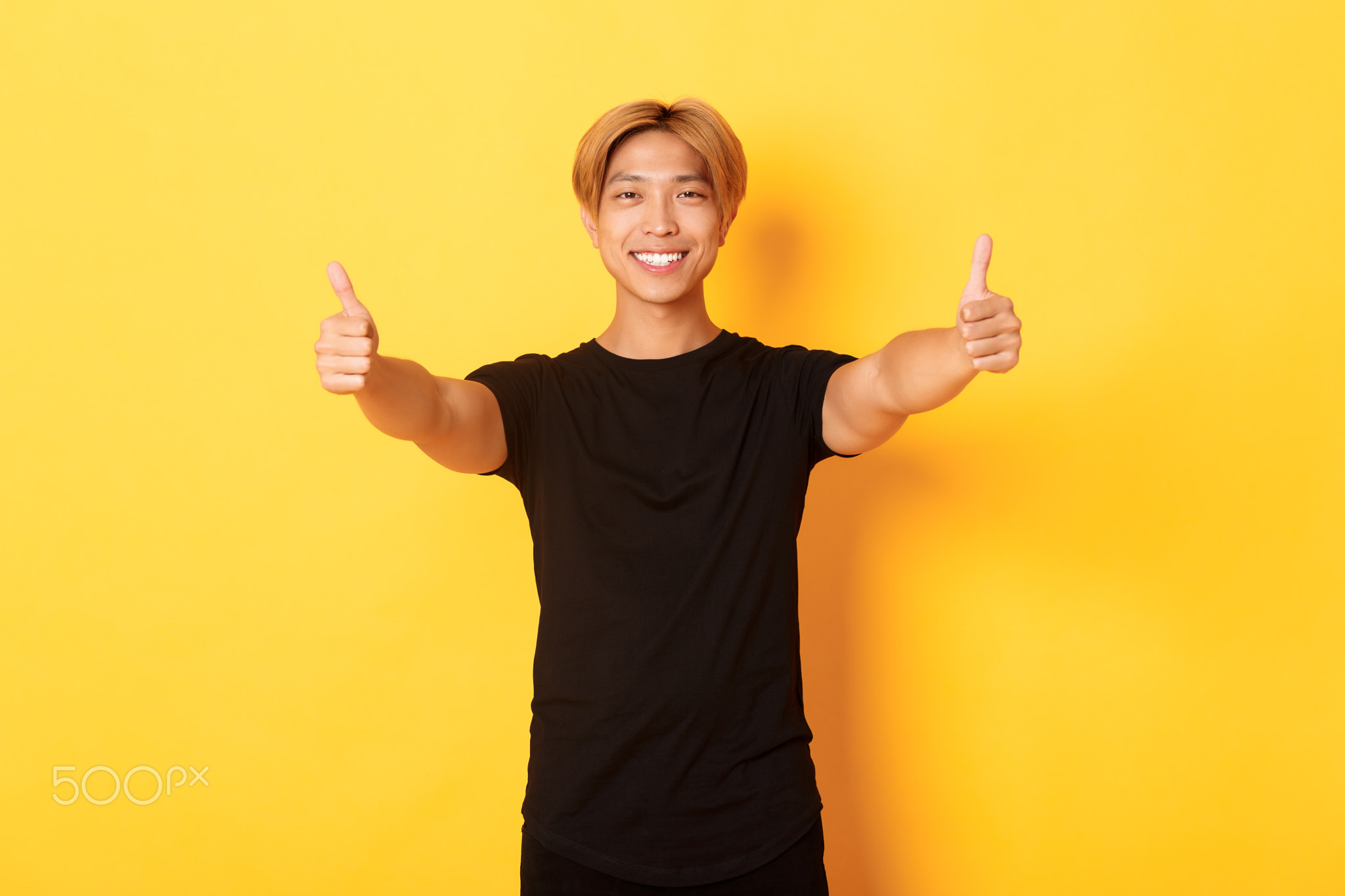 Portrait of assured handsome asian man showing thumbs-up in approval