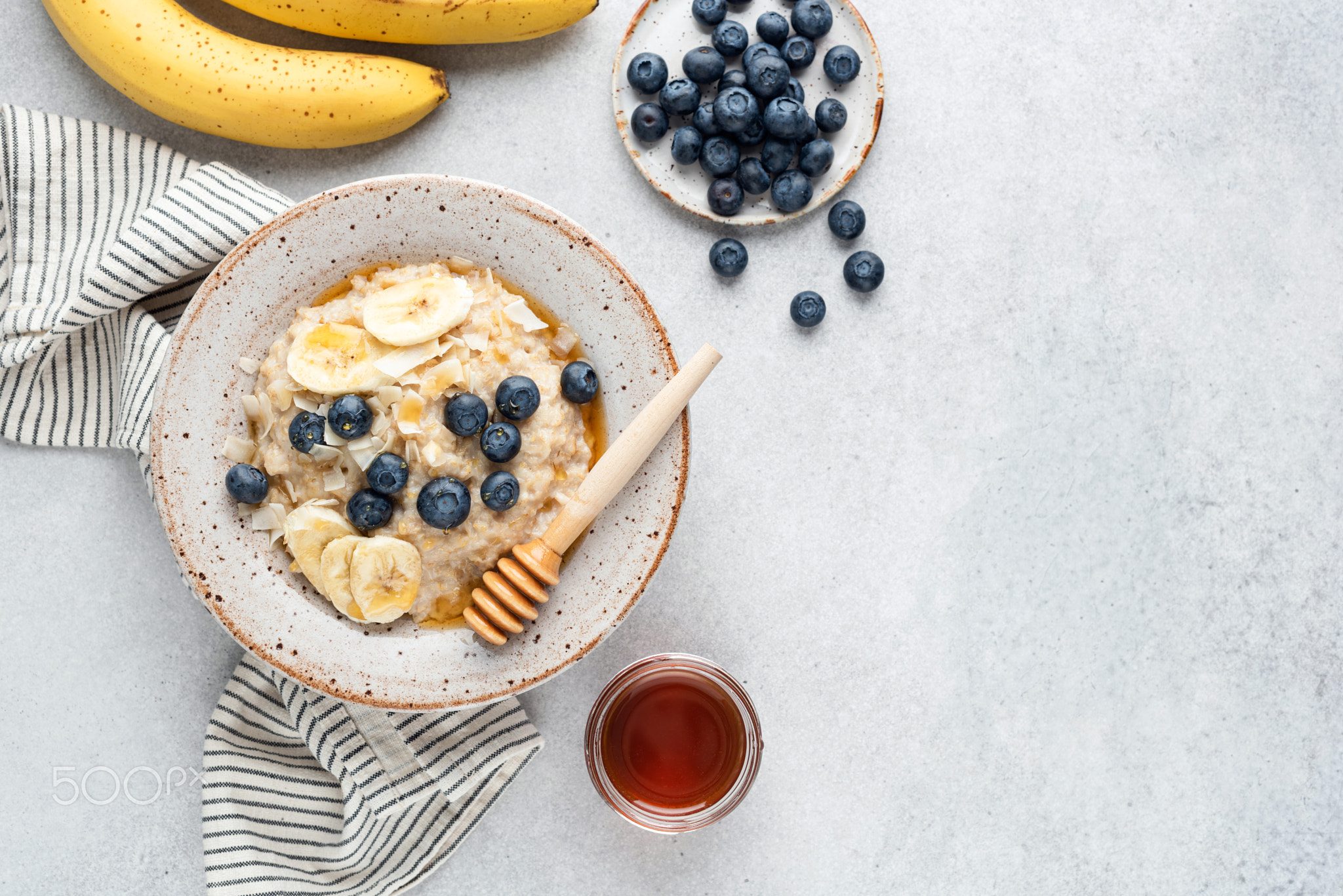 Breakfast oatmeal bowl with blueberries, banana, coconut and honey