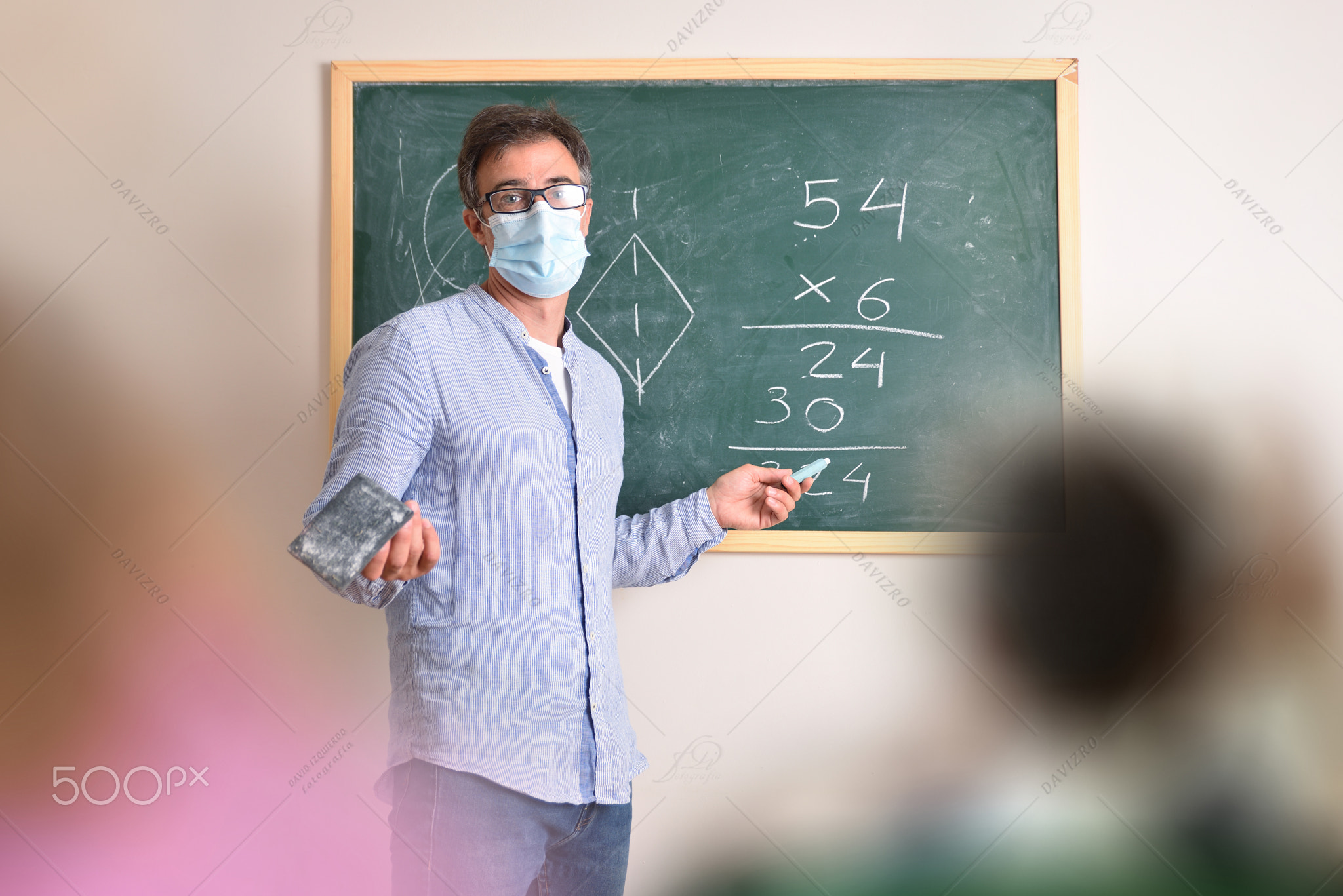 Mathematics teacher protected with mask explaining in class