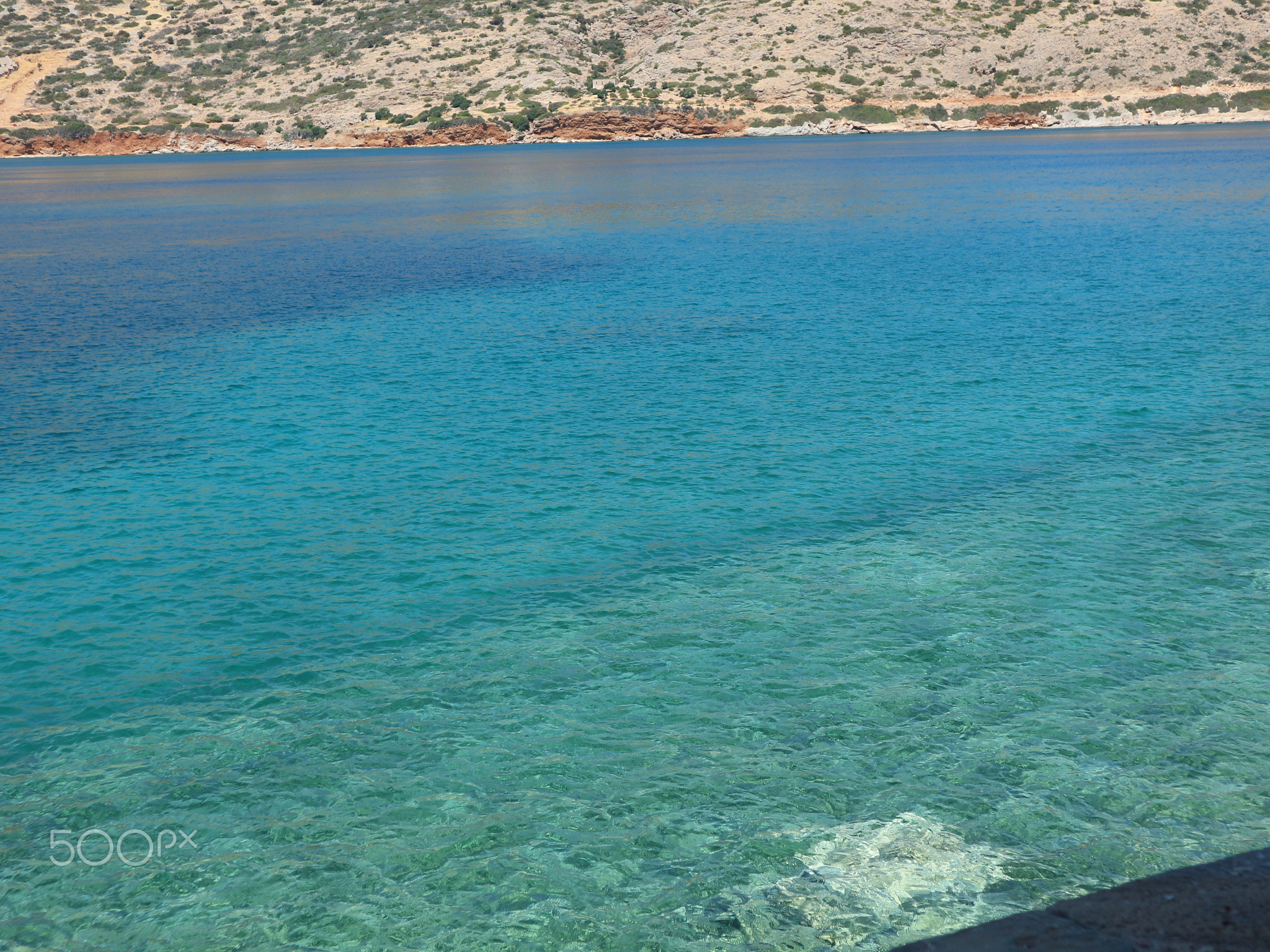 Dark and Light Blue Sea with Greenery in the Background