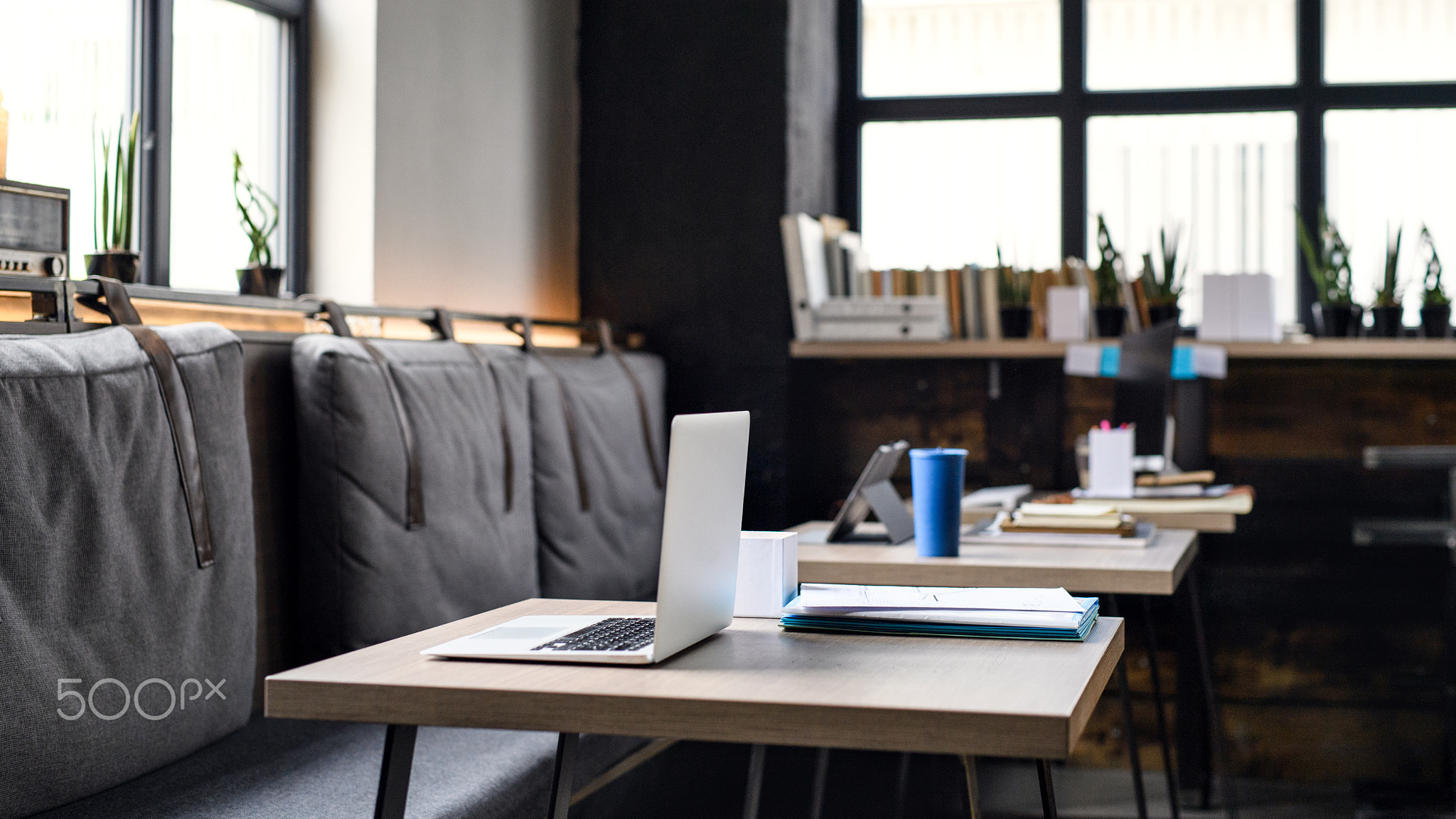 Laptops on desks in empty modern office.