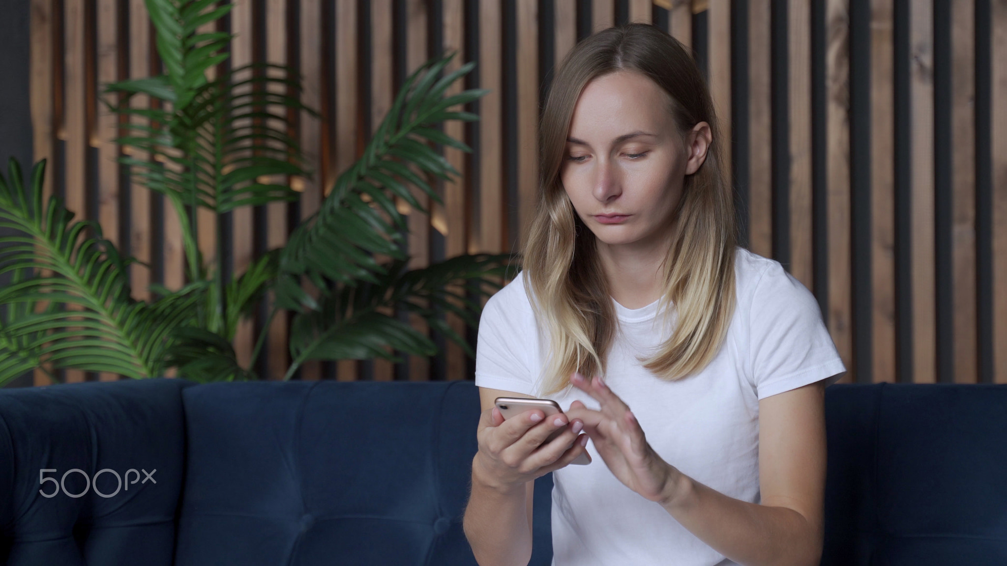 Happy woman relaxing on comfortable couch, holding smartphone in hands
