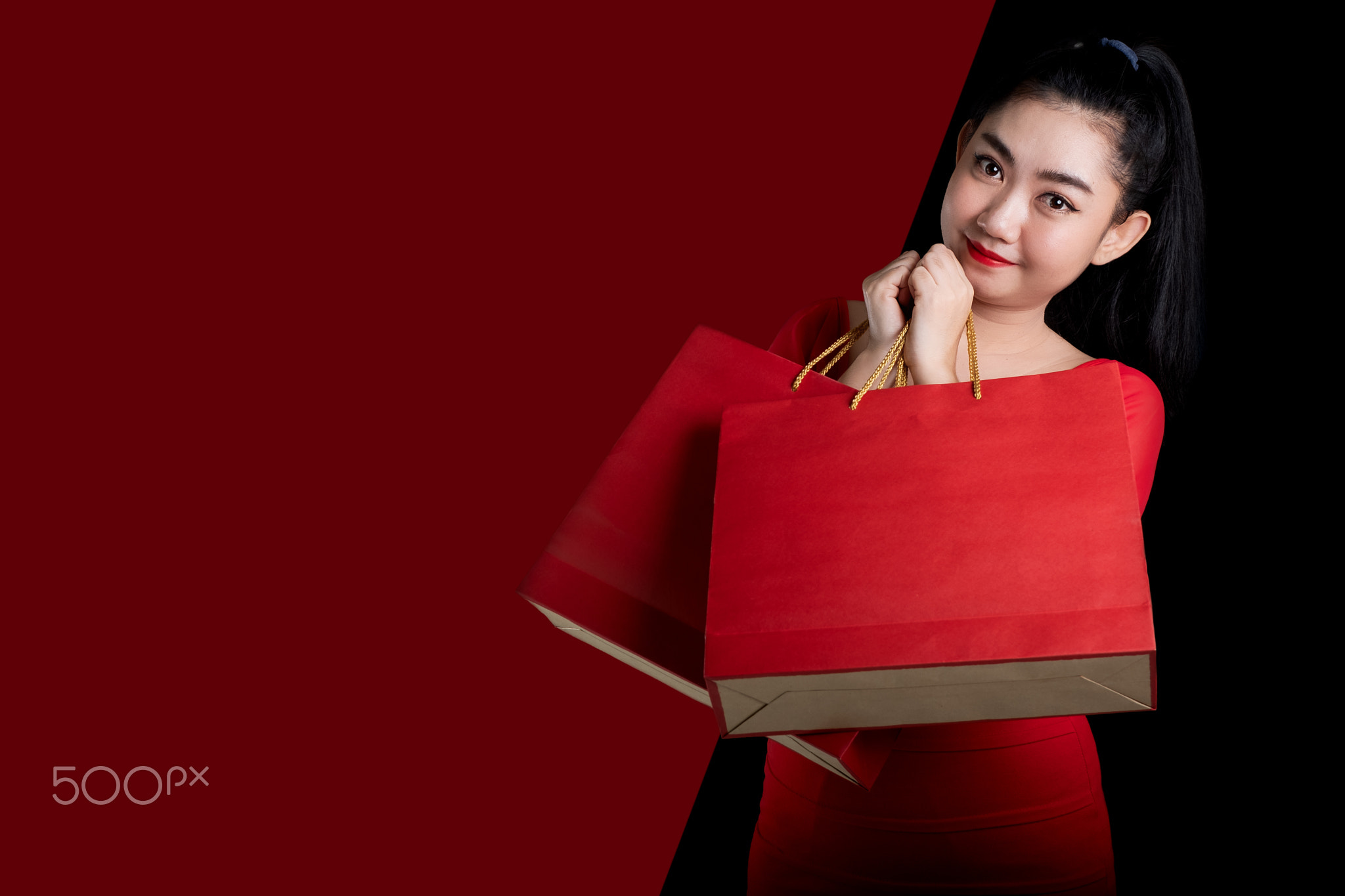 young woman wearing a red dress holding shopping bags