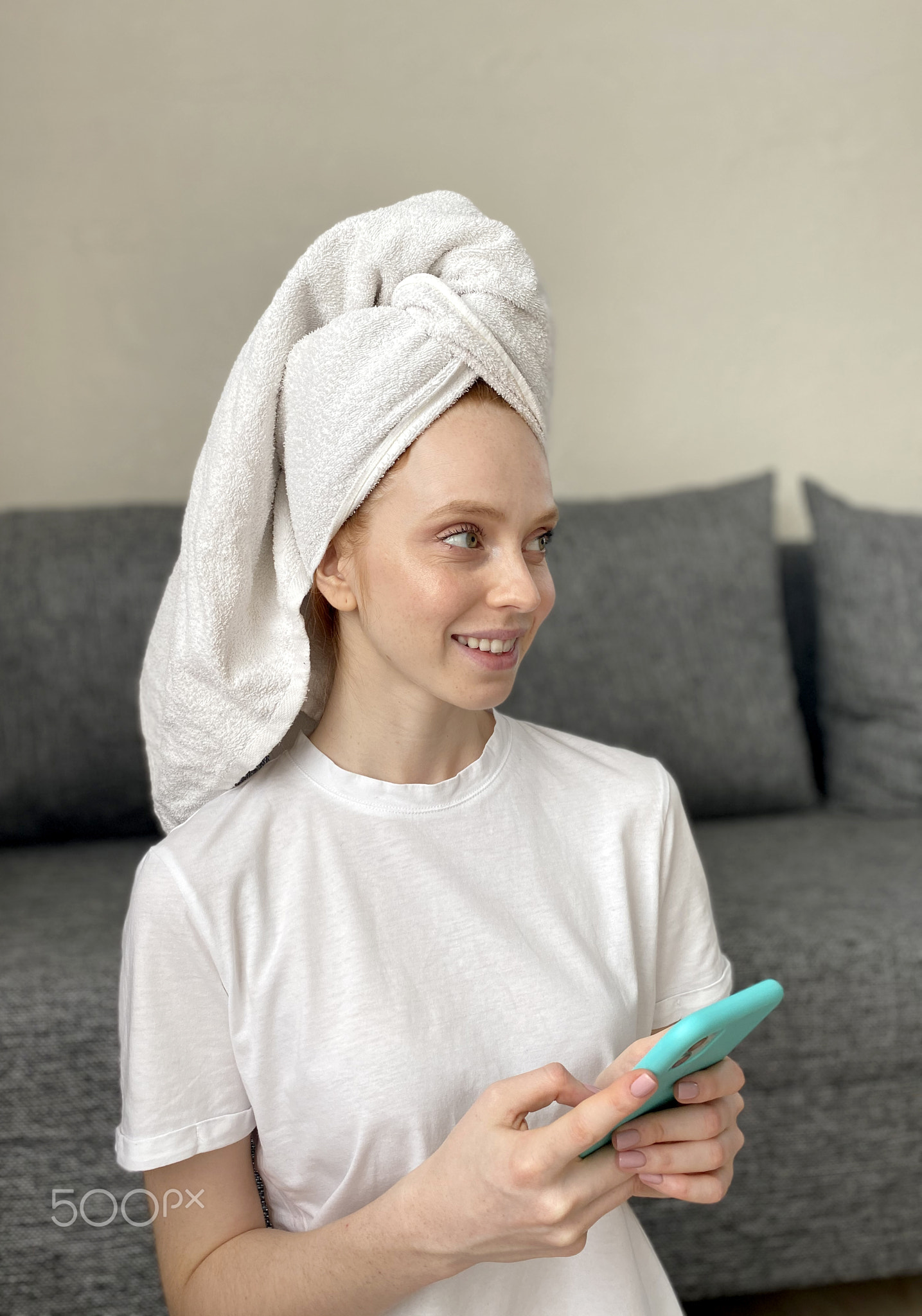 Portrait of a young woman in home clothes at home with a smartphone in