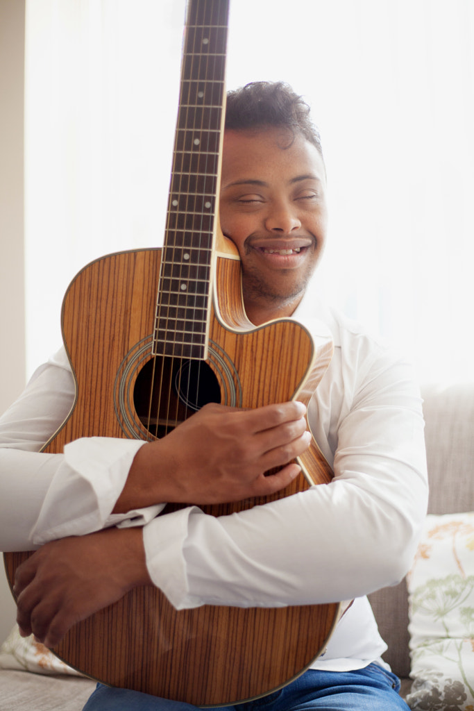 Portrait of biracial boy with Down Syndrome hugging his guitar by Anna Neubauer on 500px.com