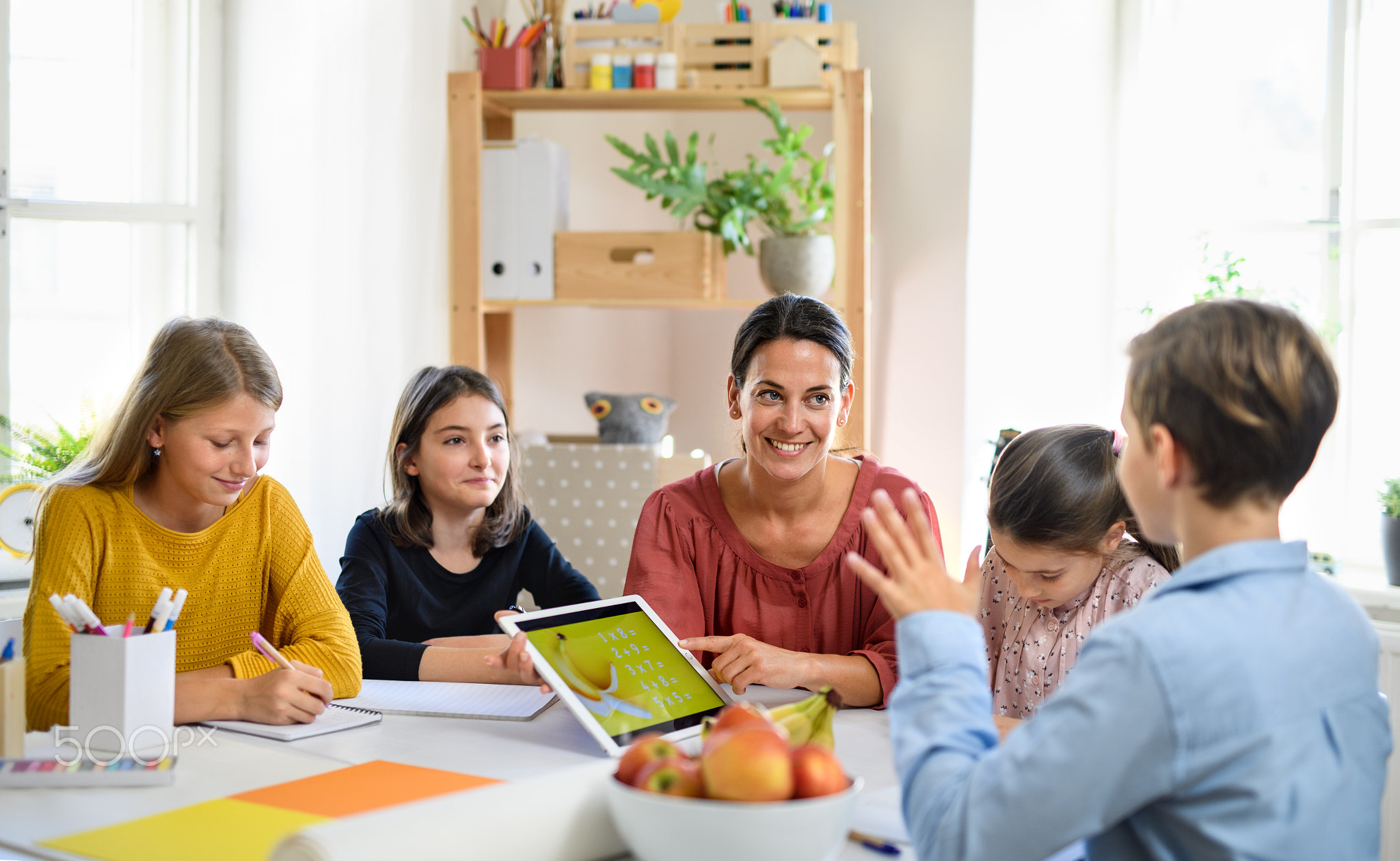 Group of homeschooling children with teacher studying indoors