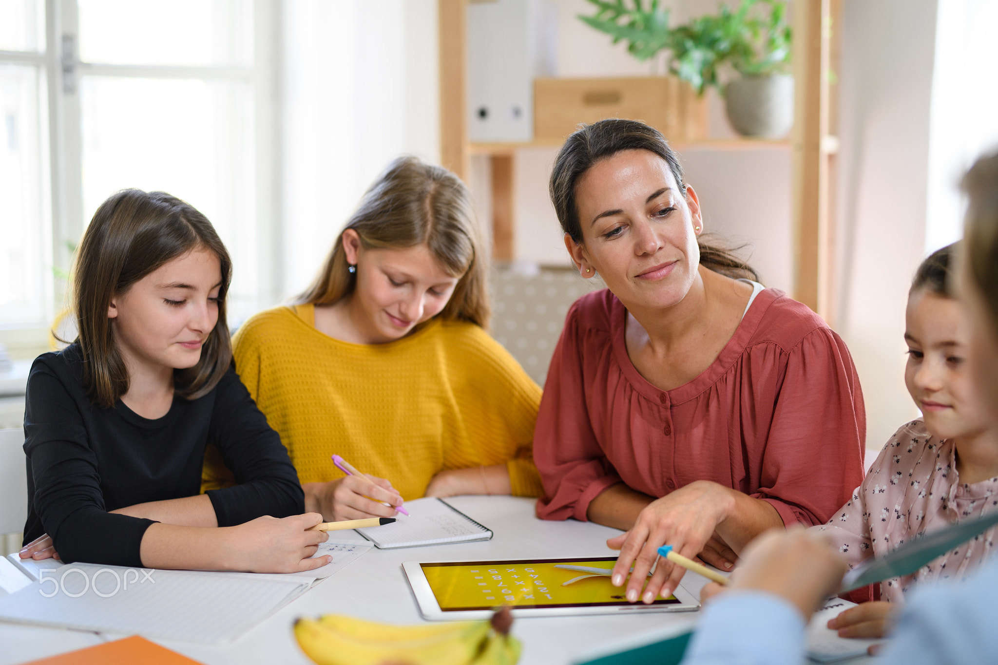 Group of homeschooling children with teacher studying indoors