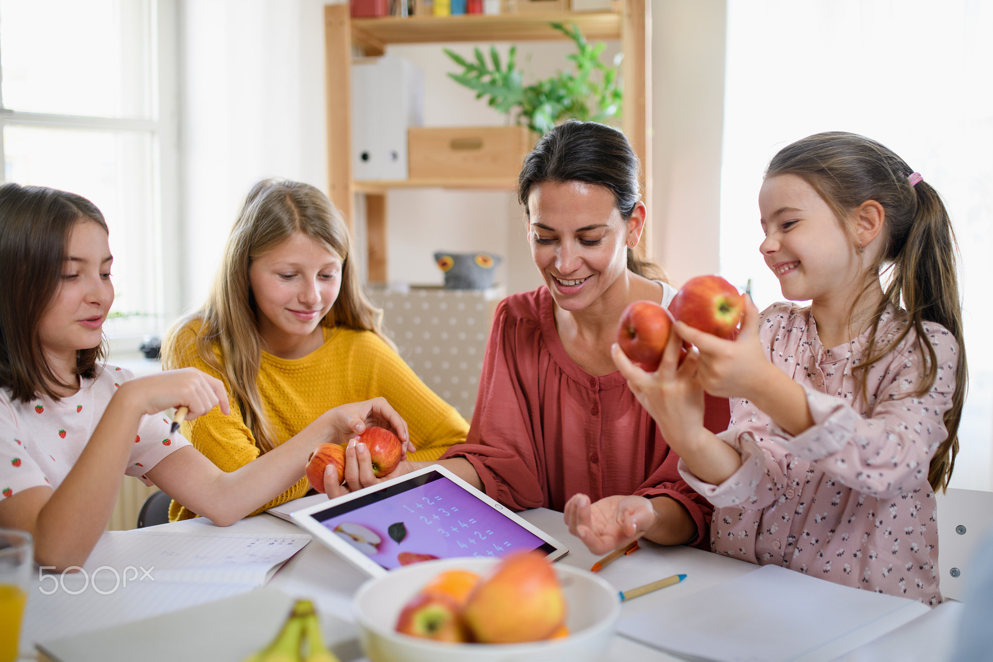 Group of homeschooling children with teacher studying indoors