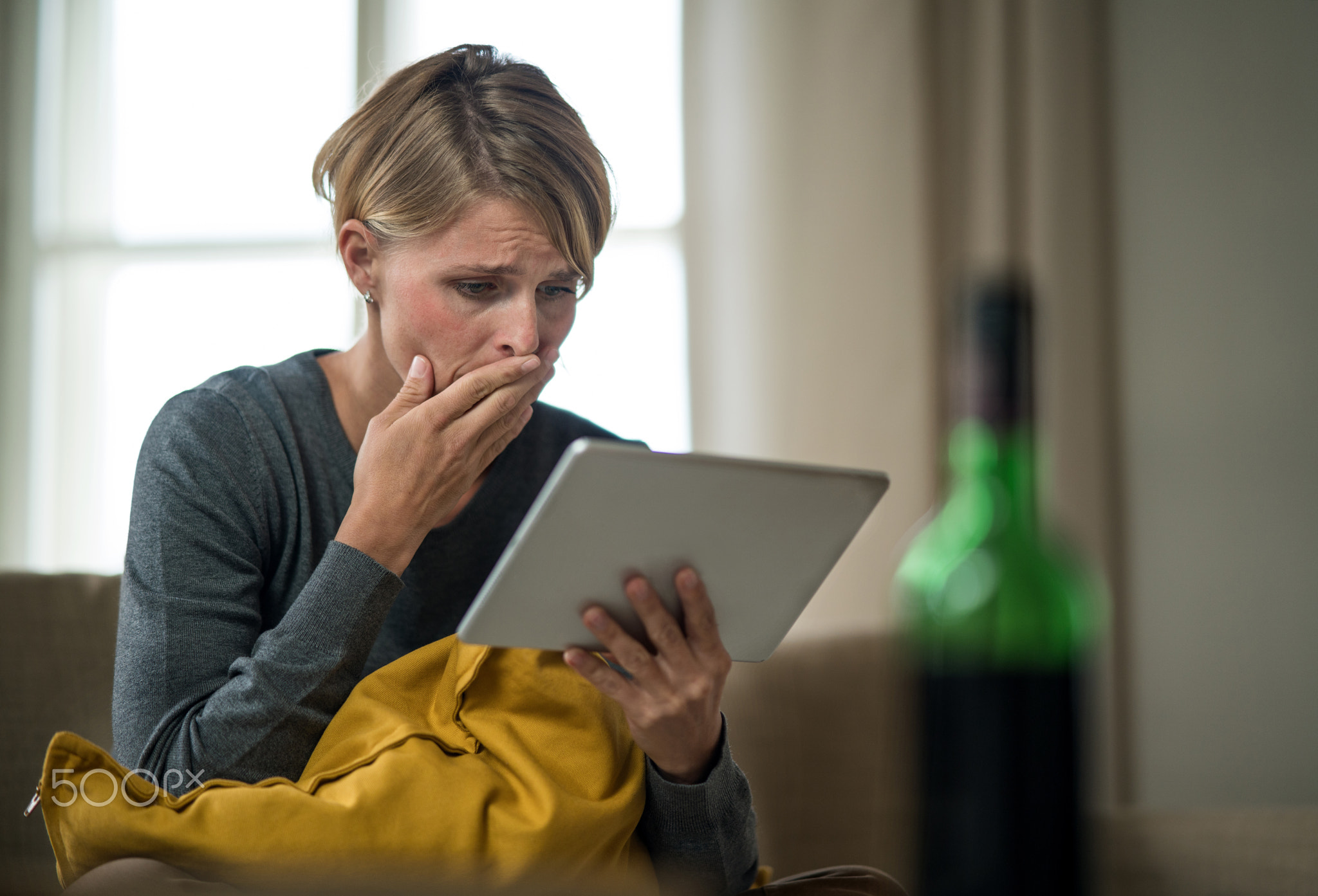 Woman with tablet indoors on sofa at home feeling stressed, mental