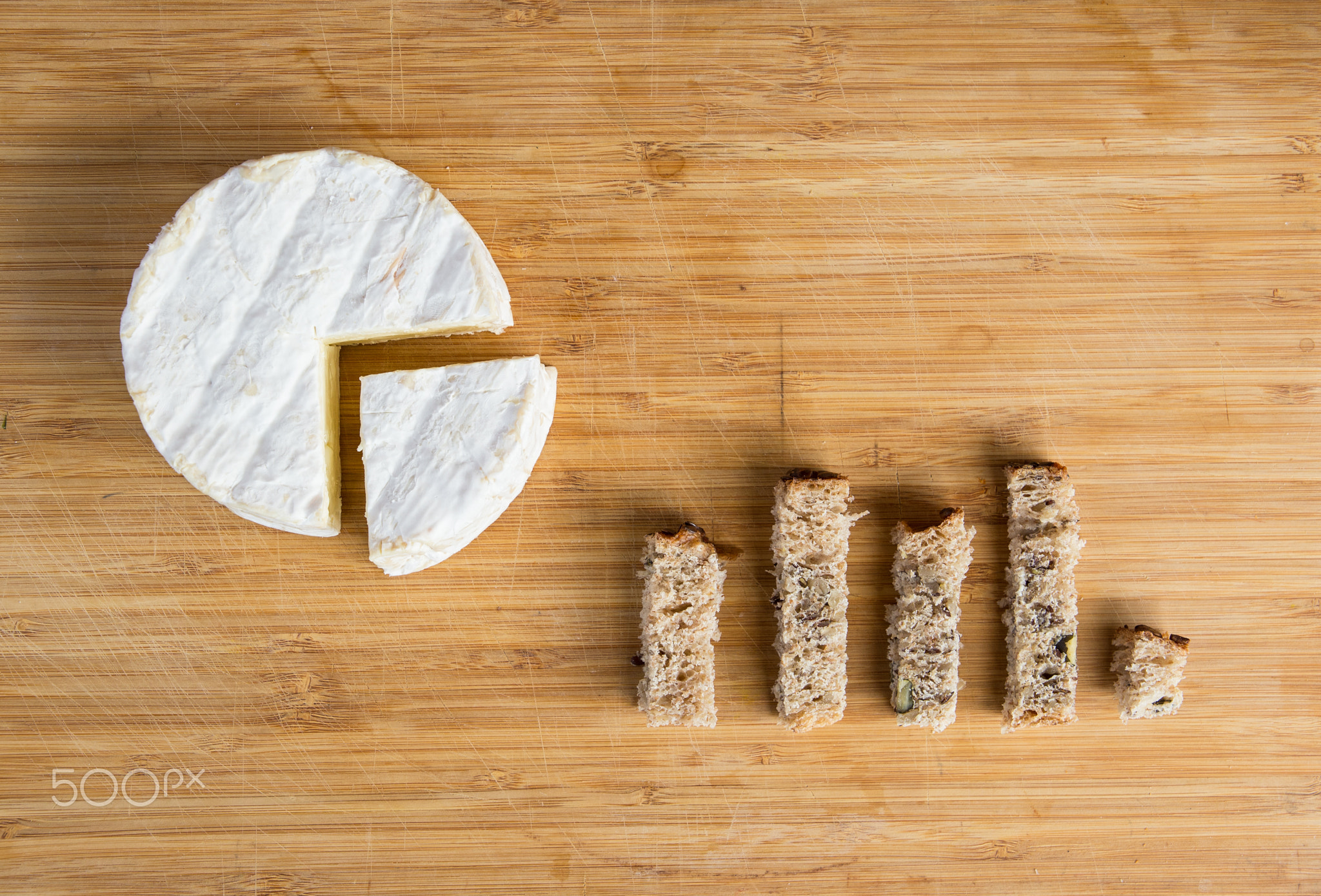 Charts made of camembert and bread on a wooden chopping board